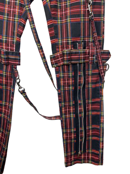 A close-up of a plaid fabric garment or accessory with red, black, yellow, and green tartan pattern, shown against a plain white background.