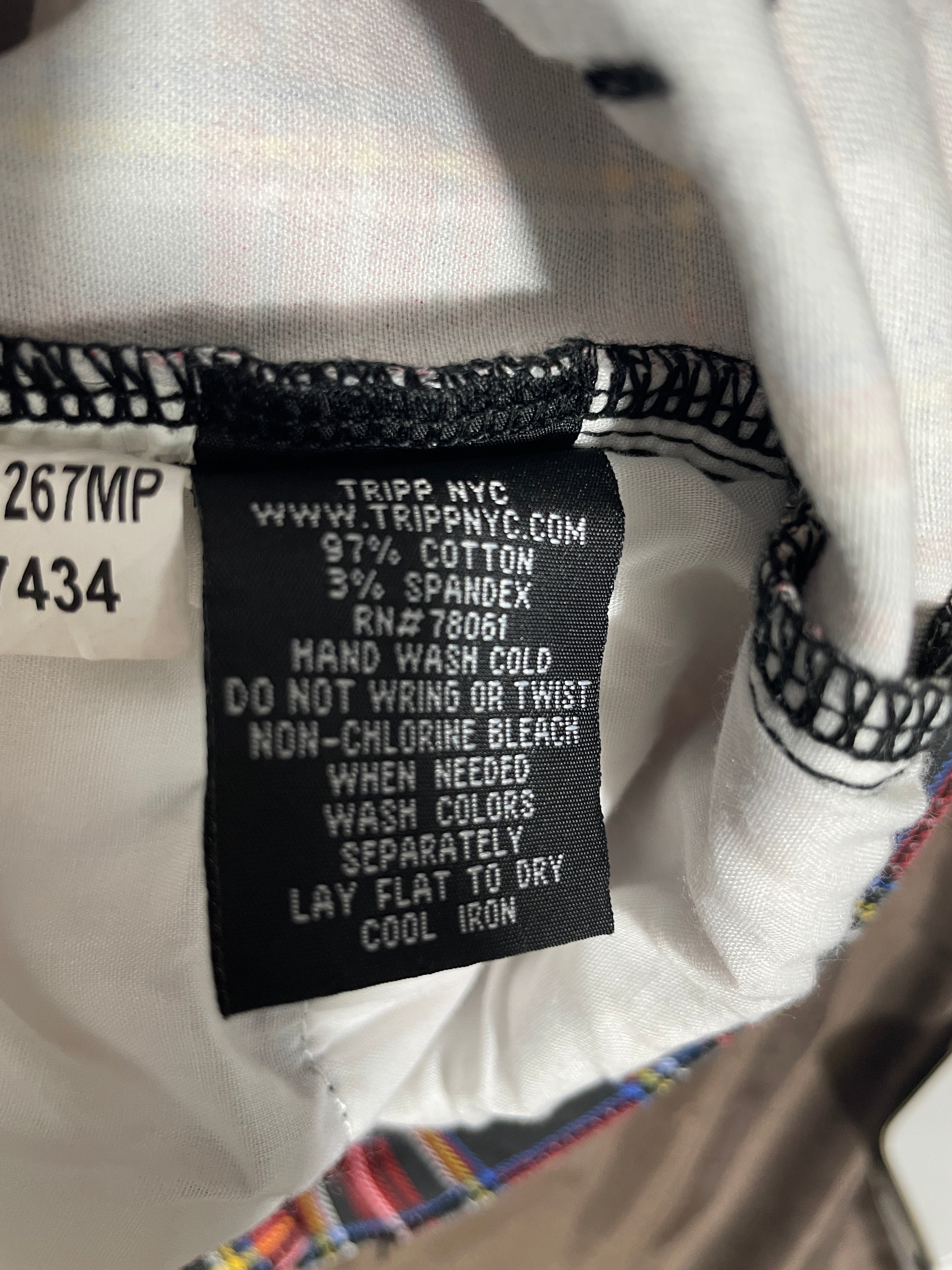 Close-up of a garment's interior neck label reading 'TRIPP NYC WWW.TrippNyc.com 97% cotton 3% spandex' on white fabric.