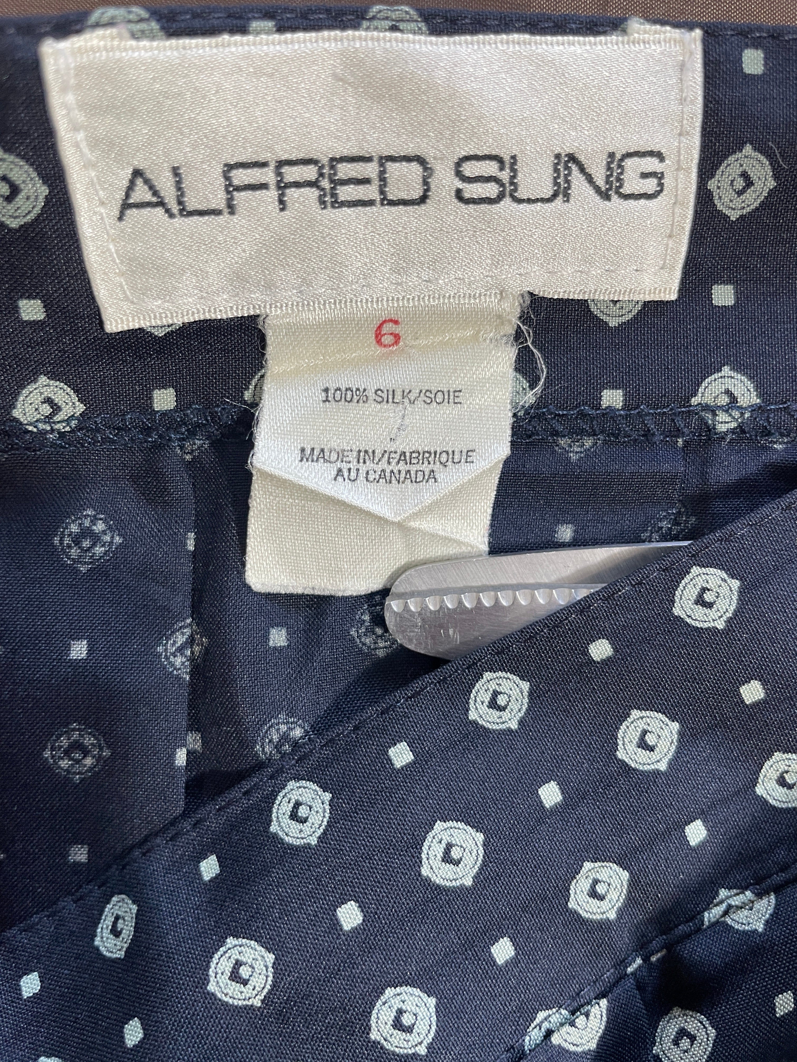 Close-up of the inside neck label of an Alfred Sung garment, showing the brand name, size 6, and fabric details of a navy blue silk with a white geometric pattern.