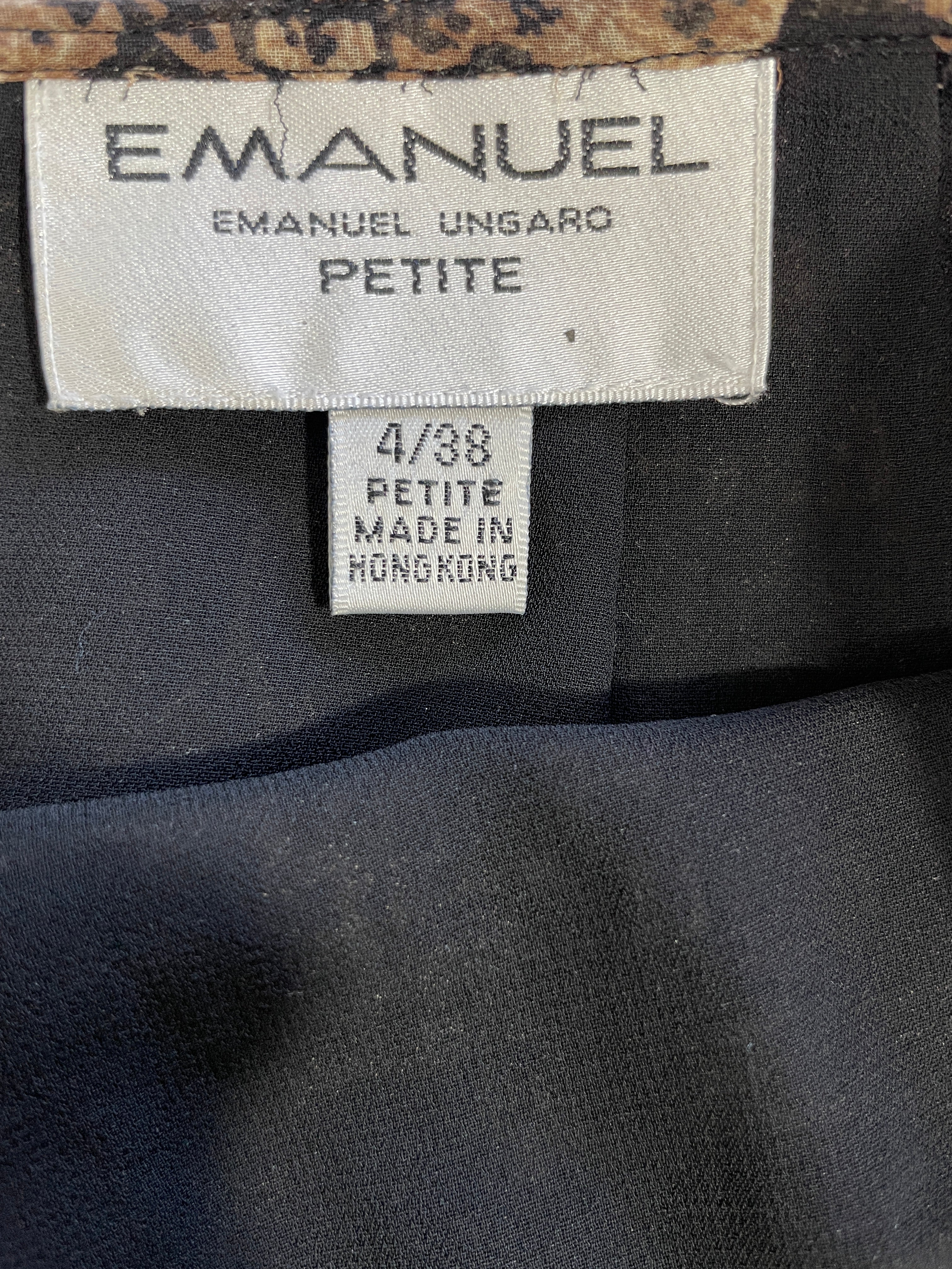 Close-up of a clothing label reading EMANUEL UNGARO PETITE, with size 4/38 and Made in Hong Kong, attached to a dark navy garment.