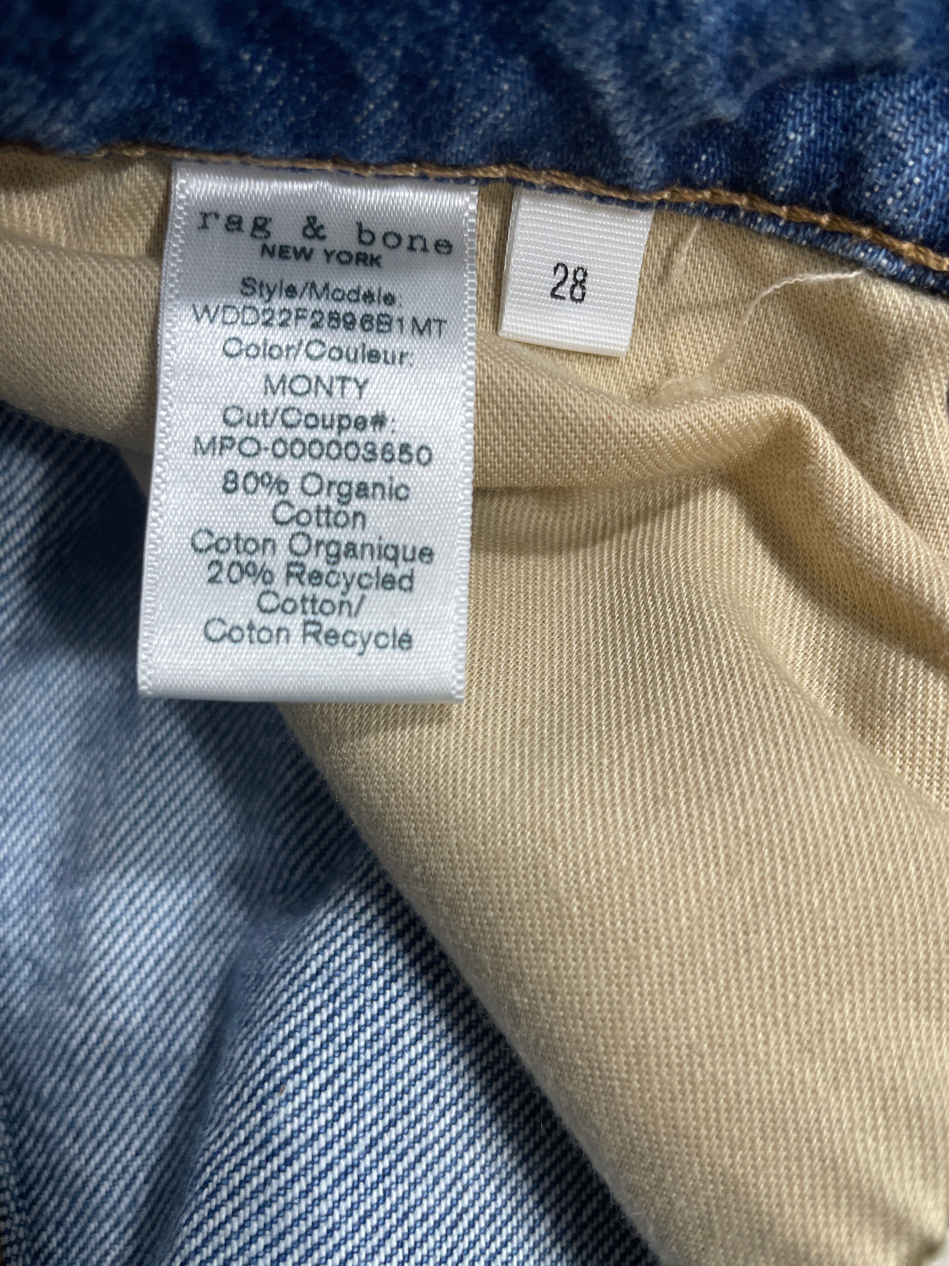 Close-up of a garment's interior label and fabric lining. The label reads 'rag & bone' and shows size '28' along with material details.