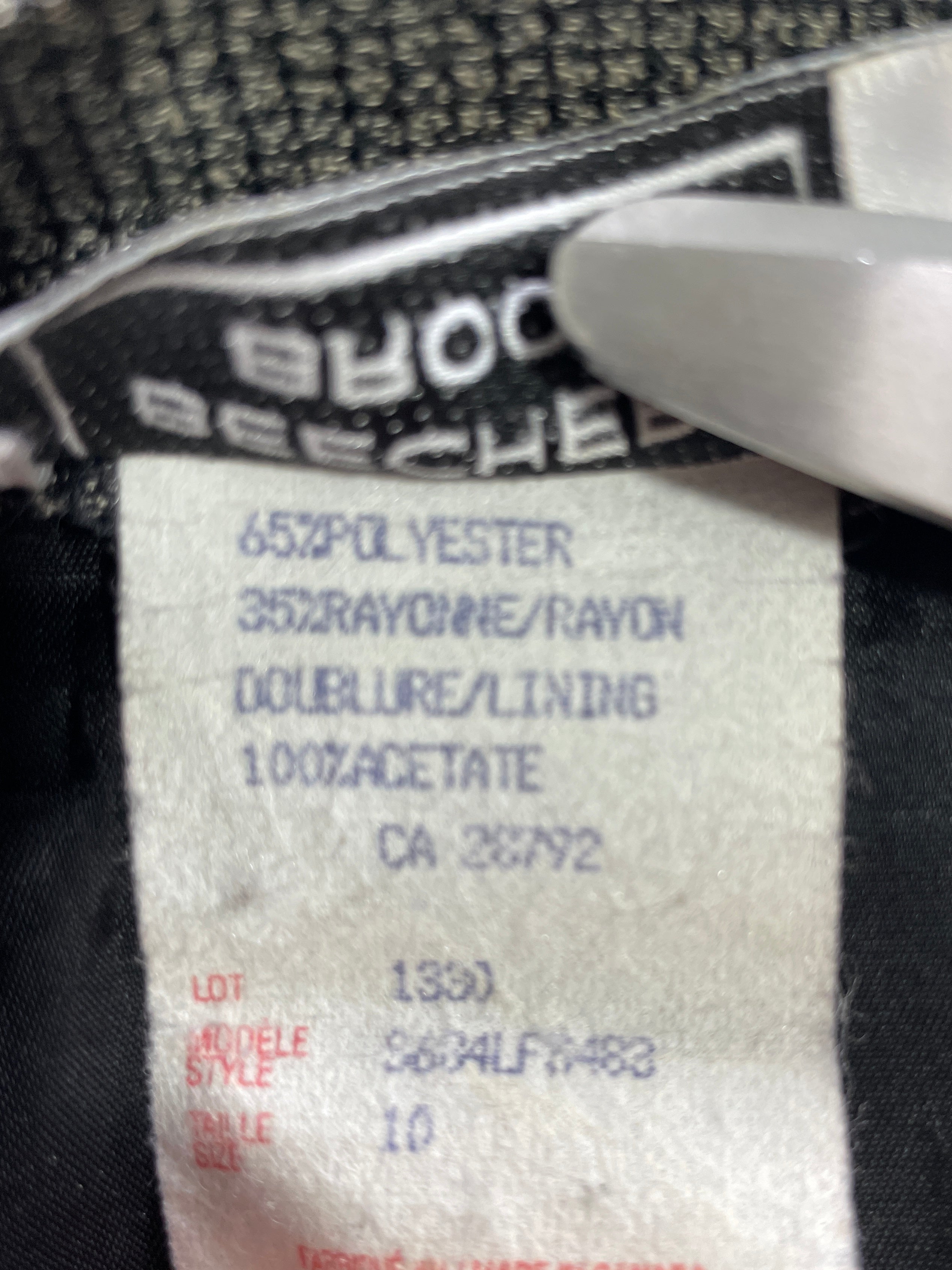 Close-up of a garment's interior neck label showing fabric composition and care instructions, with a finger touching the label.