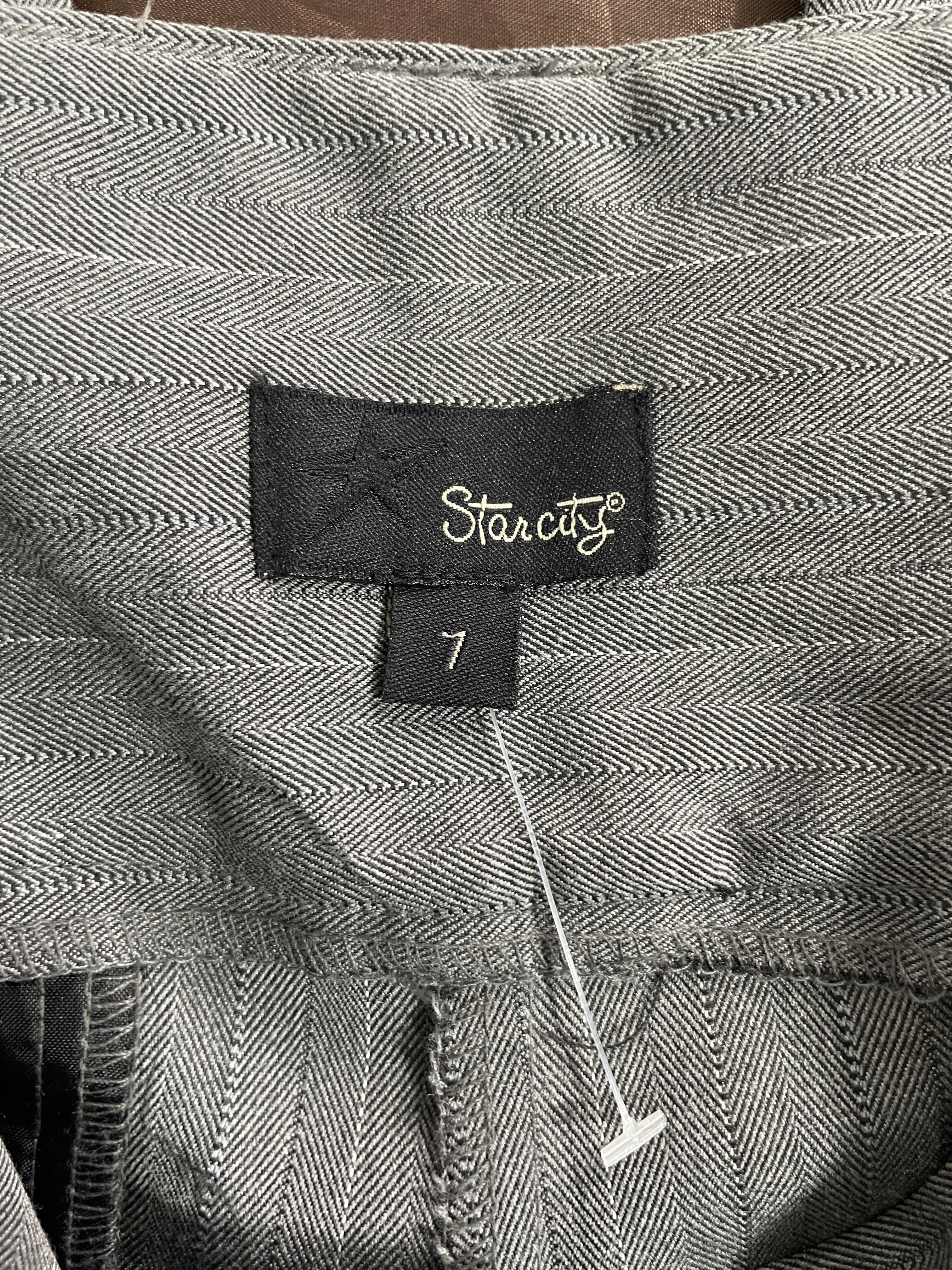 Close-up of a gray herringbone-patterned garment with a black fabric brand label reading 'Starcity' and a size tag showing '7'.