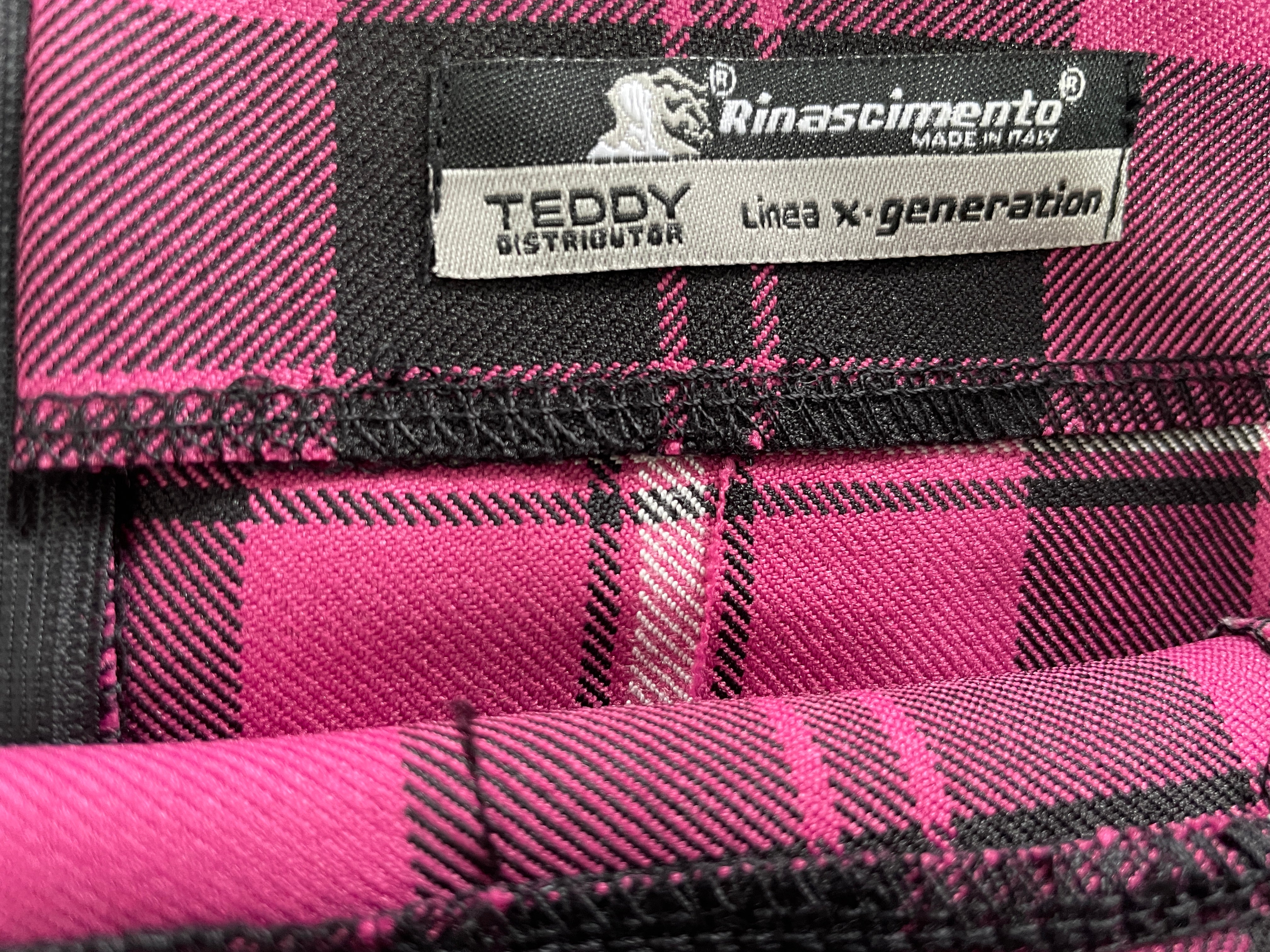 Close-up of a pink and black plaid fabric with a sewn-in label reading TEDY Linen x Generazione Rinascimento.