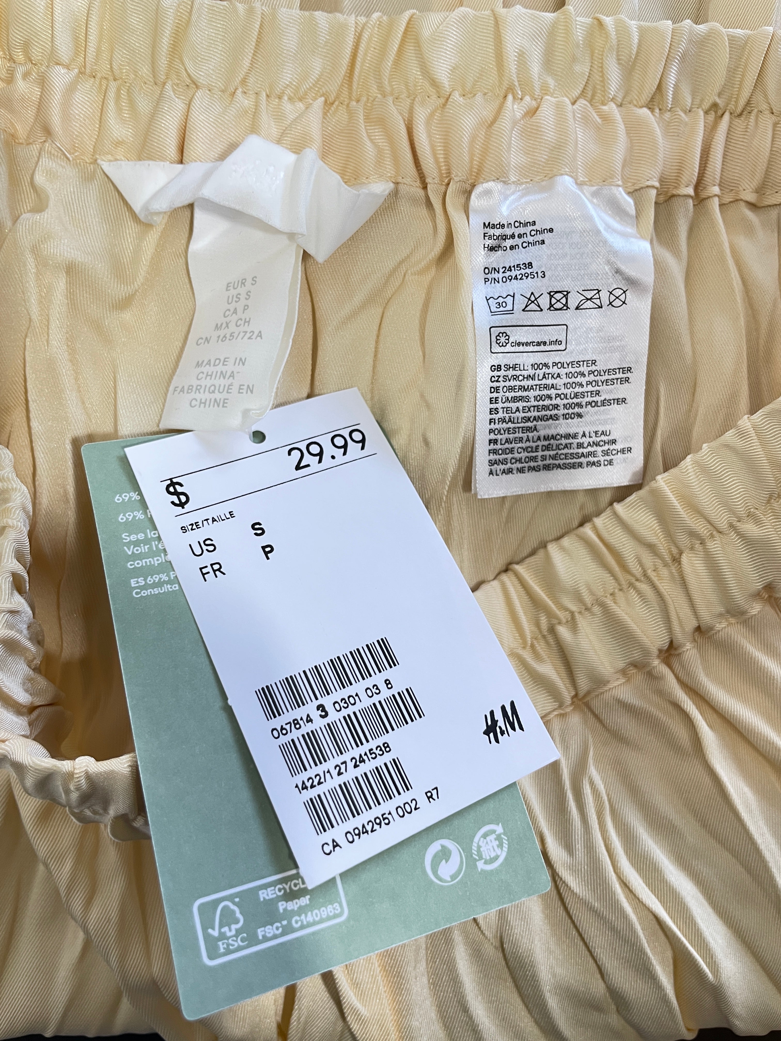 Close-up of H&M cream pleated skirt with original $29.99 price tag and fabric labels
