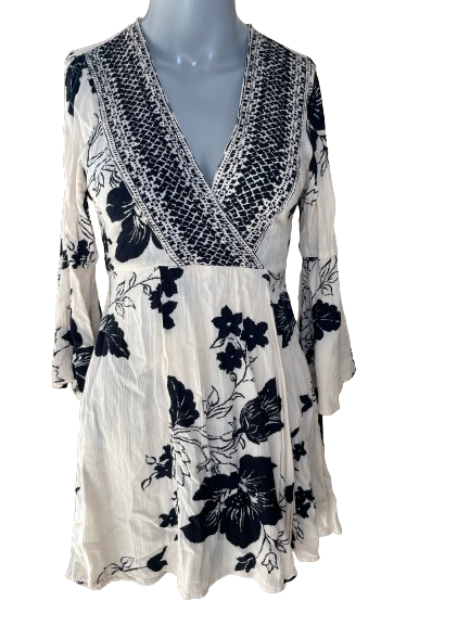 Billabong Cream Black V-Neck Mini Dress displayed on a mannequin, featuring a floral pattern with a V-neck and tie-back design.