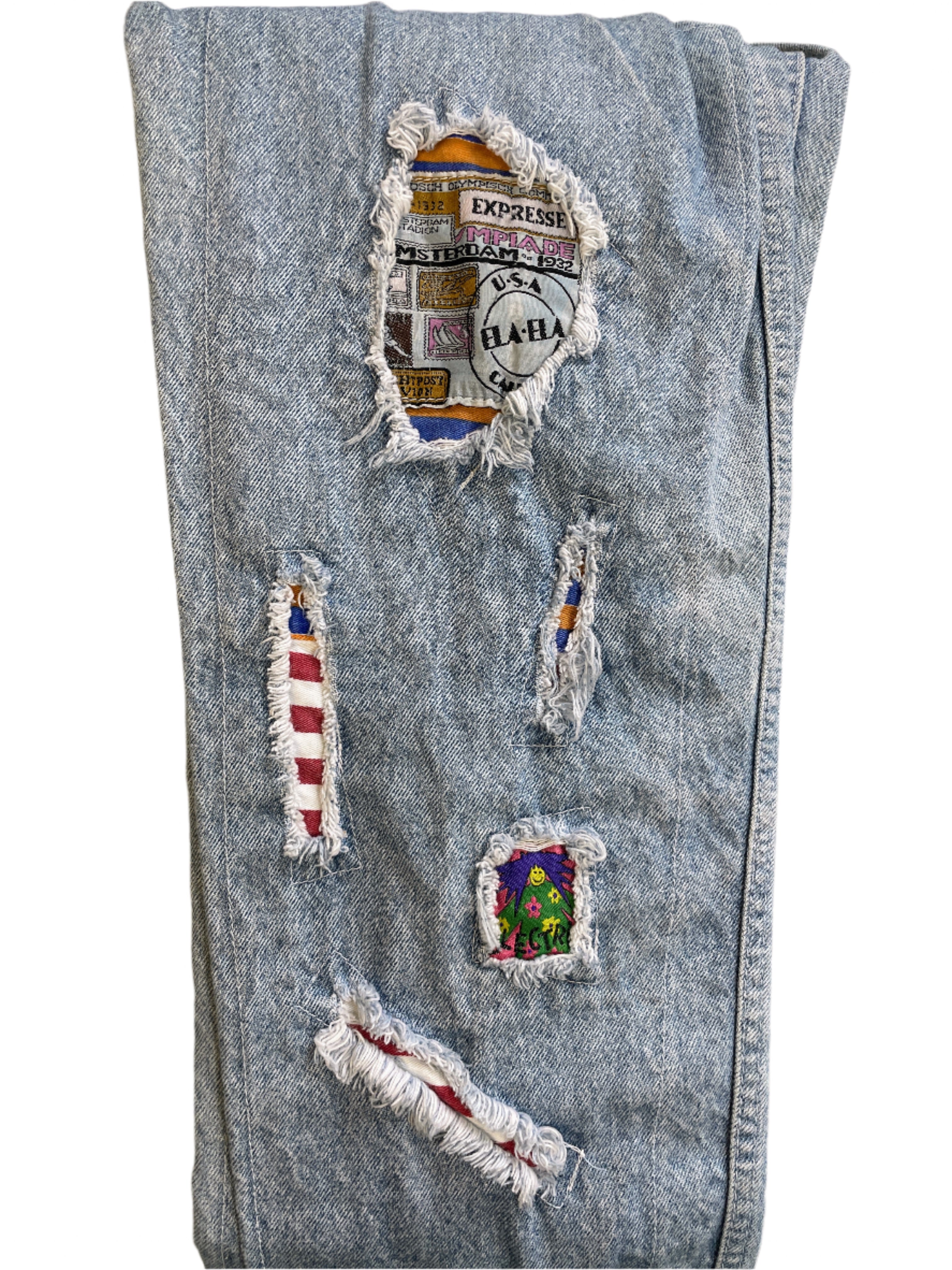 Blue denim jeans with various patches on a beige surface