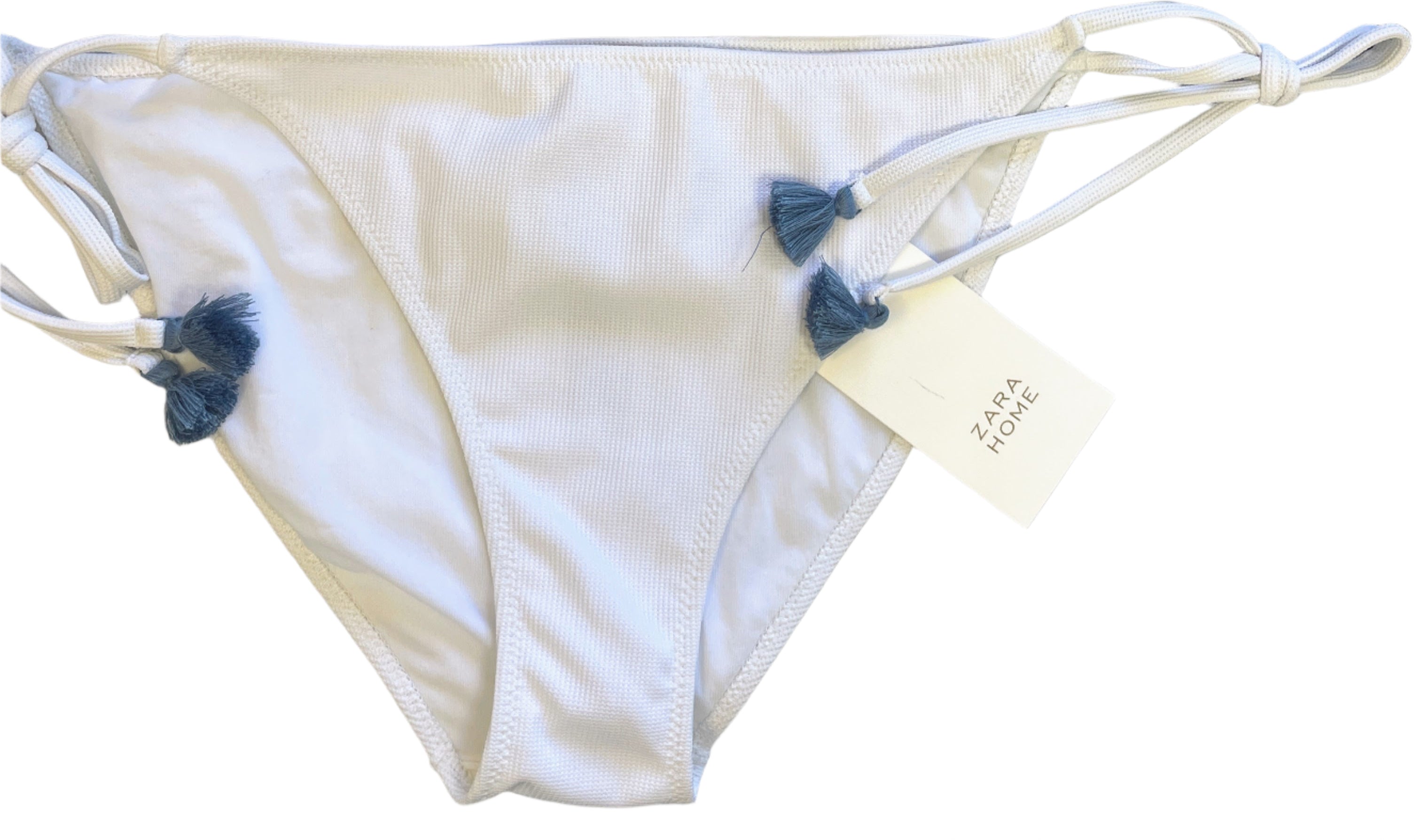 White bikini bottom with tags on a light gray surface