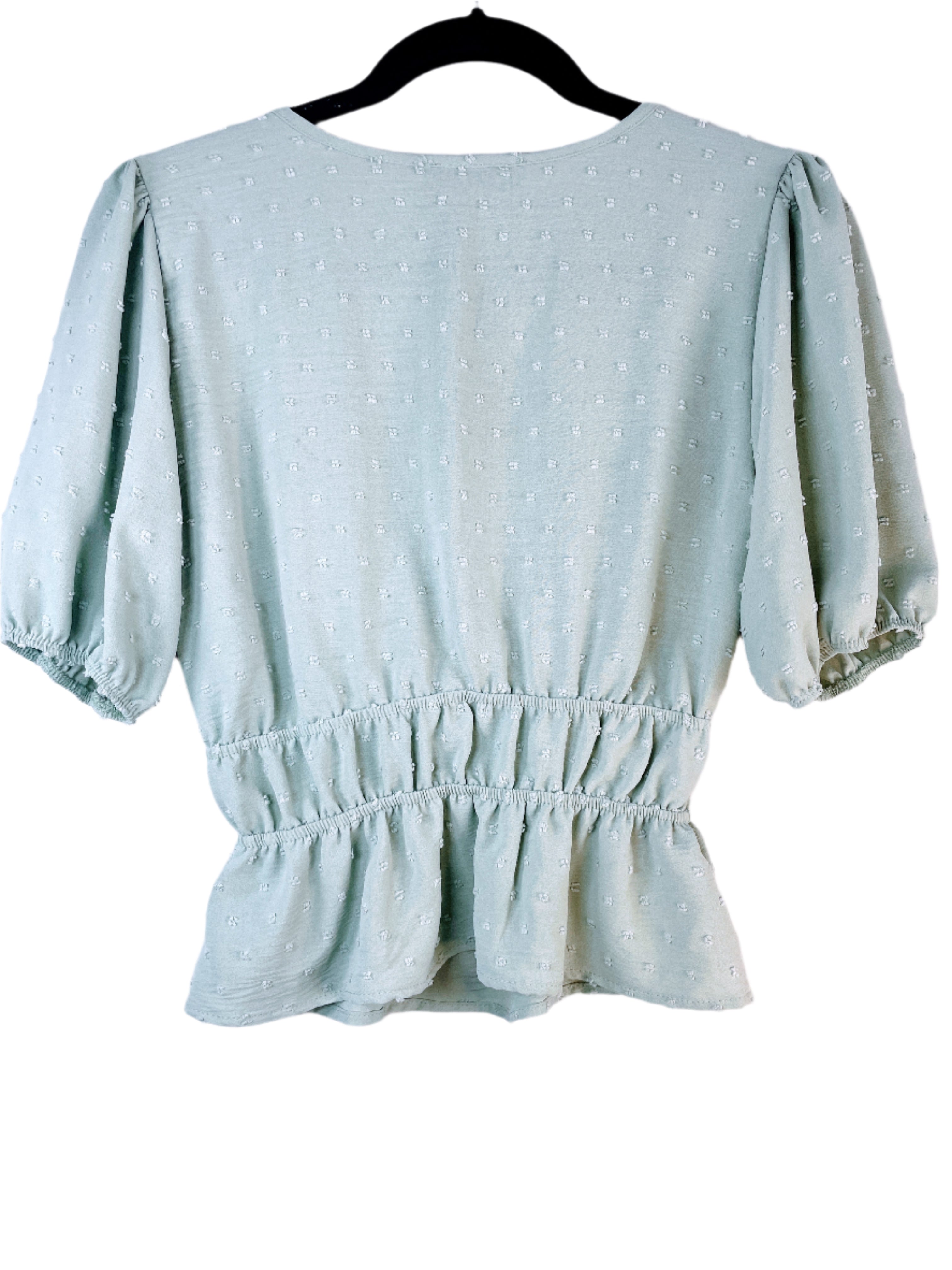 Light green blouse with ruffled hem and puff sleeves on a white background