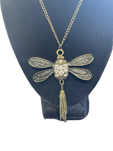 Dragonfly-shaped necklace with tassel on a blue stand