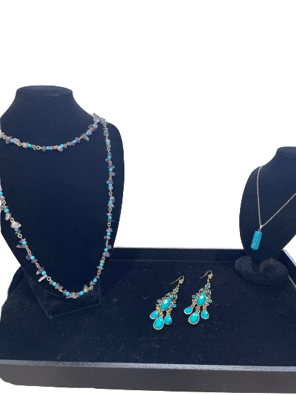 Jewelry set with necklace, earrings, and pendant on a blue stand against a white background