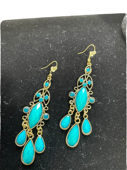 Turquoise earrings with gold accents on a black background