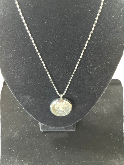Silver necklace with a round pendant on a black stand