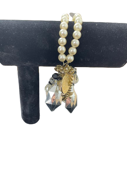 Chunky faux pearl charm bracelet with gold-tone coins and faceted crystal-style beads hanging on a stand