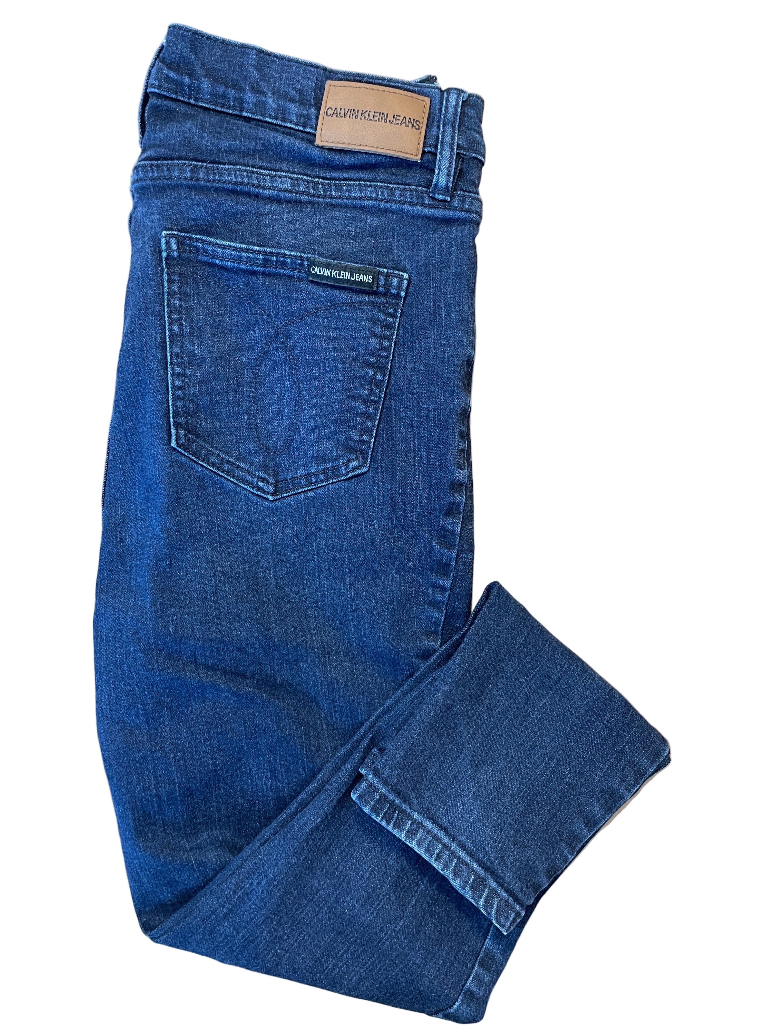 Folded view of Calvin Klein dark wash skinny jeans with leather patch and logo tag