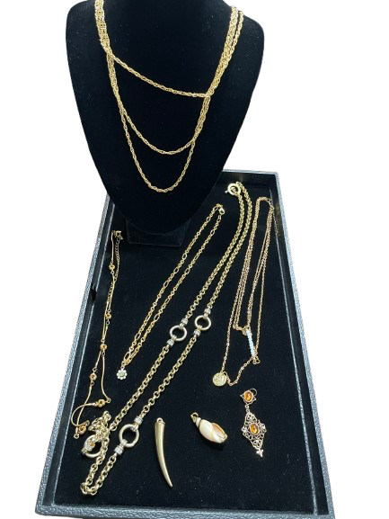 Gold-tone necklace and pendant collection displayed on tray