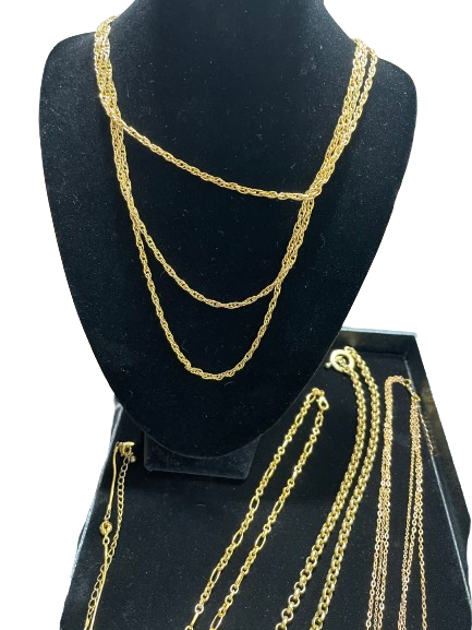 Gold chains displayed on a black mannequin bust and stand.