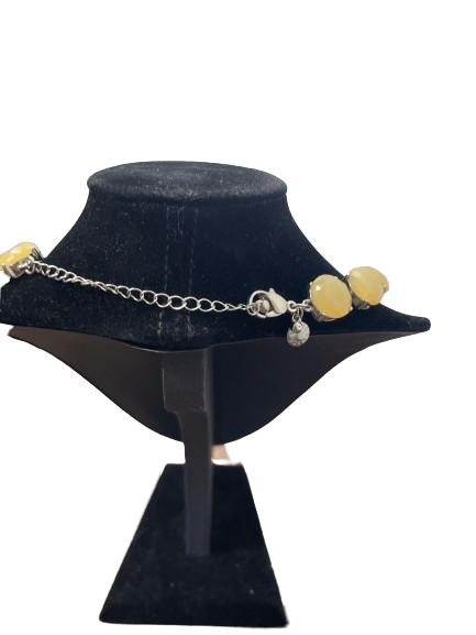 Necklace with yellow beads and silver chain on a black velvet stand