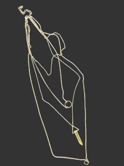 Gold tone layered necklace laid flat showing three chain lengths and geometric pendants