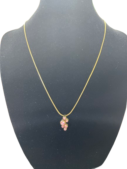 Gold tone necklace with pink crystal cluster pendant on display bust