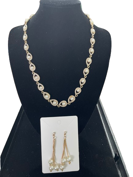 Faux pearl and rhinestone gold tone necklace with matching drop earrings on display