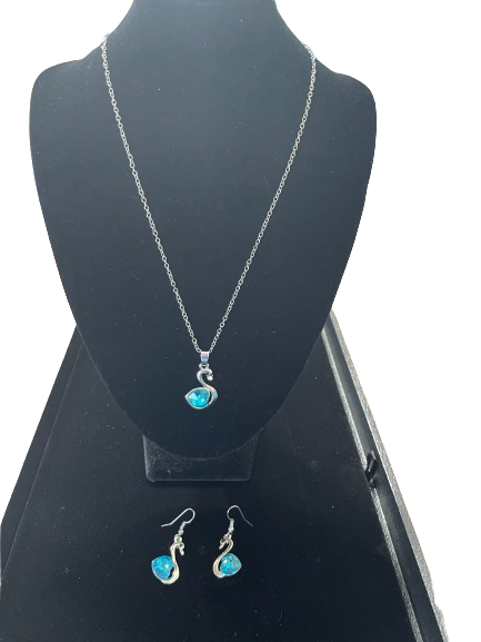 Silver swan necklace with blue crystal heart pendant displayed on black bust