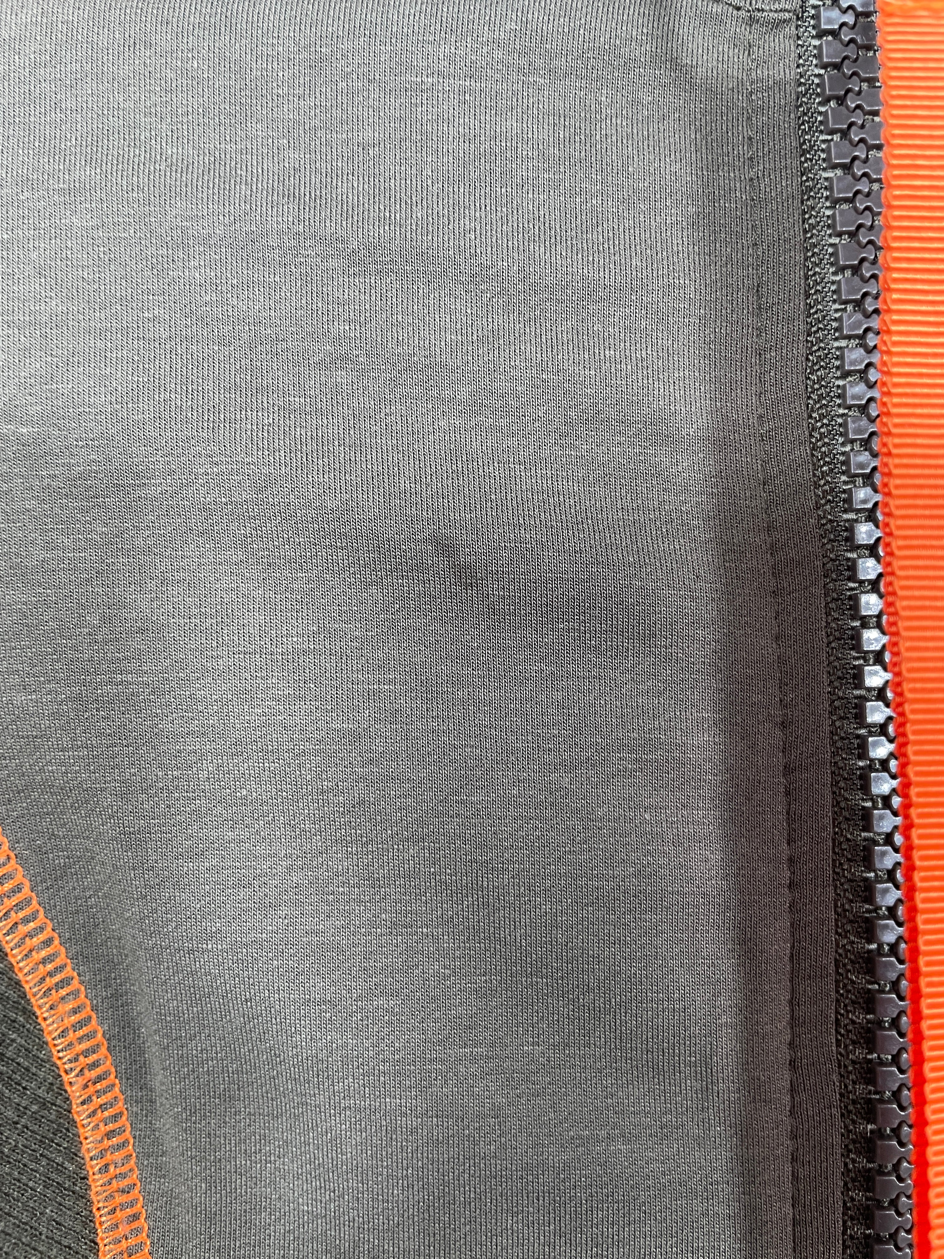 Close-up of a gray dress with orange zipper and trim, small stain