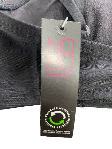 A close-up of a black garment tag hanging from a black fabric item, with the brand name 'NO BO' in pink and a green recycled material logo near the bottom.