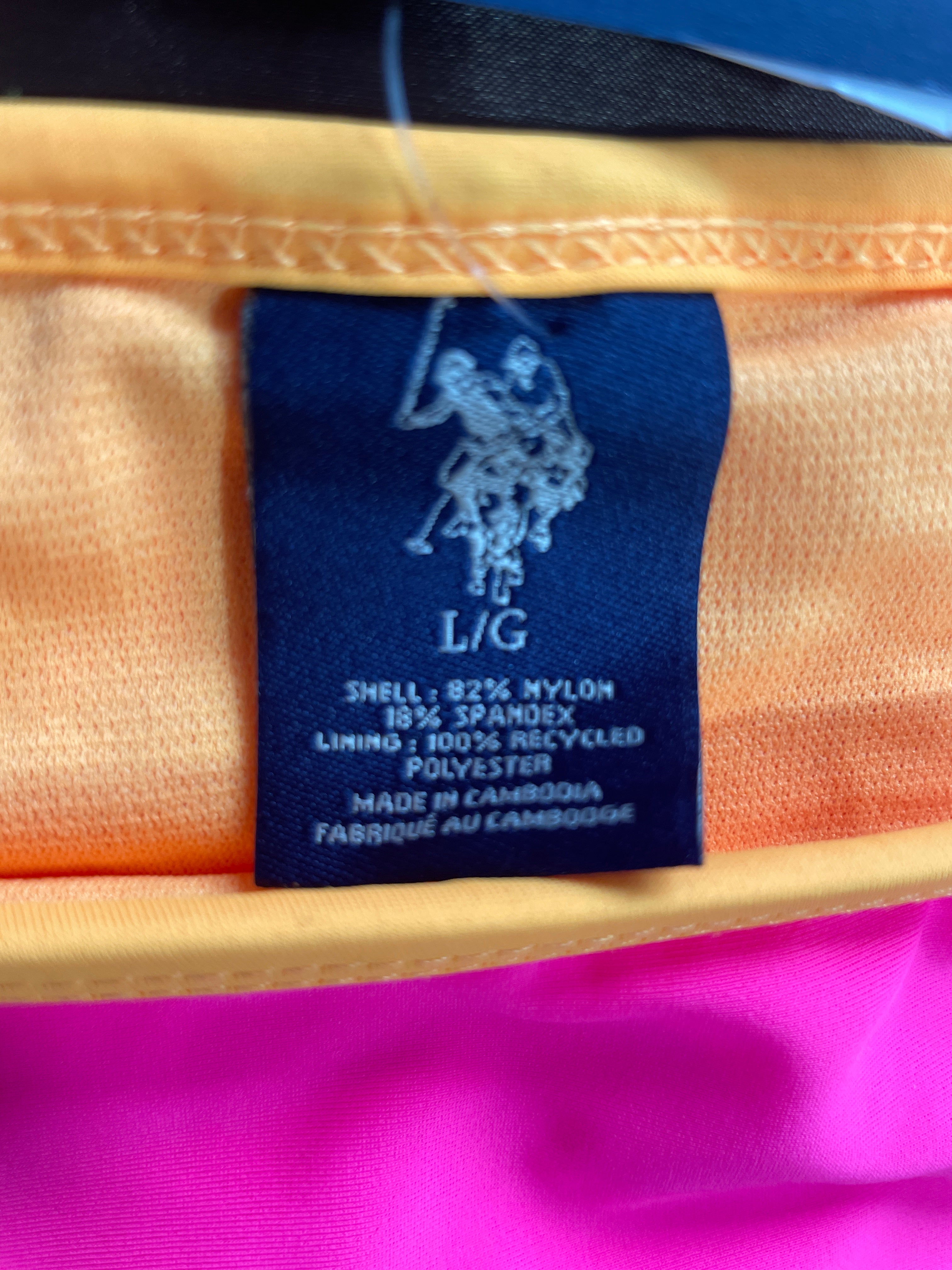 Close-up of a garment's interior label showing the Polo Ralph Lauren pony logo and text, with a yellow-orange lining above and bright pink fabric below.