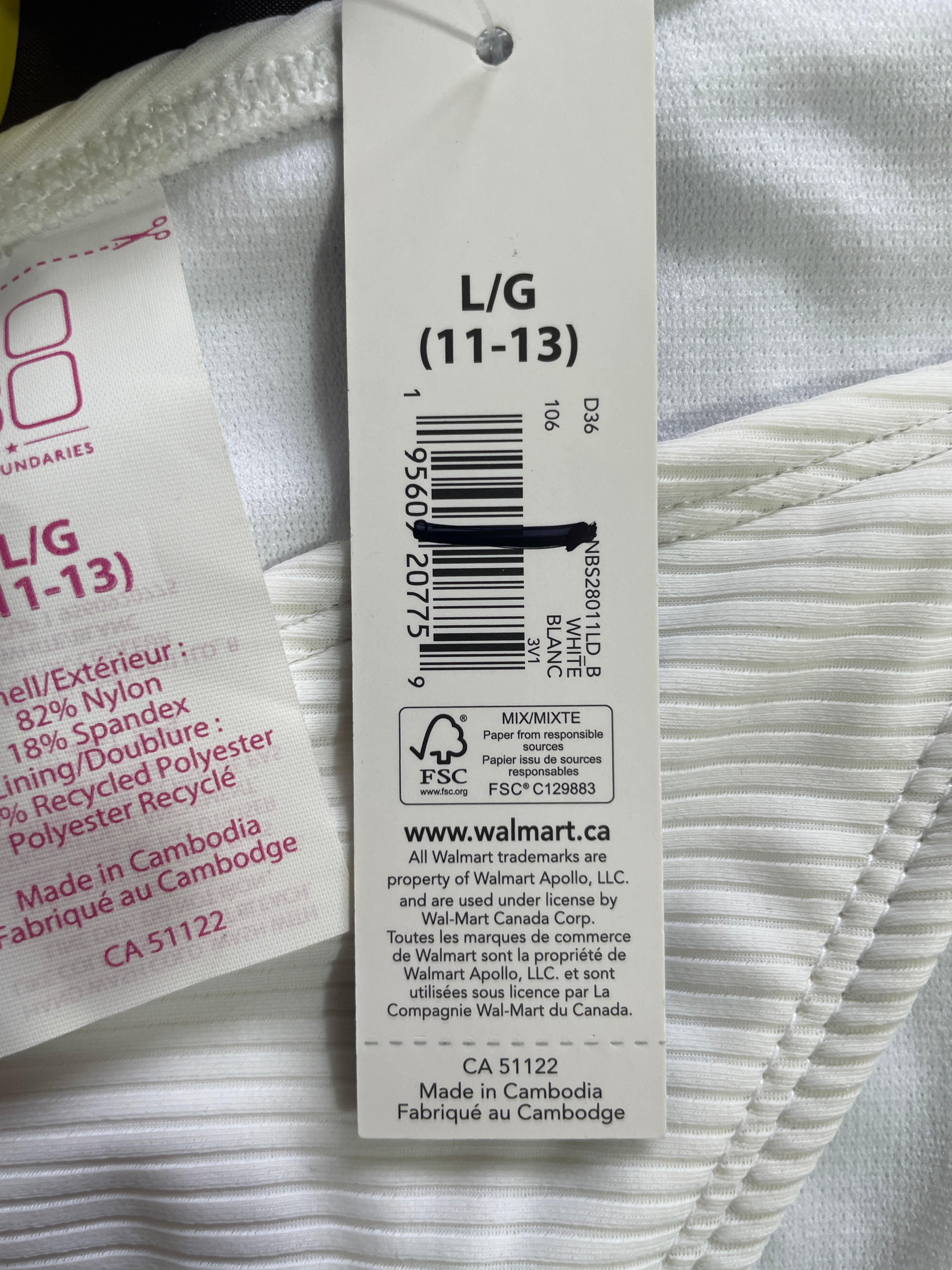 A close-up of a white ribbed fabric item with attached retail tags, including a central white Walmart product tag showing barcode and text for L/G (11-13).