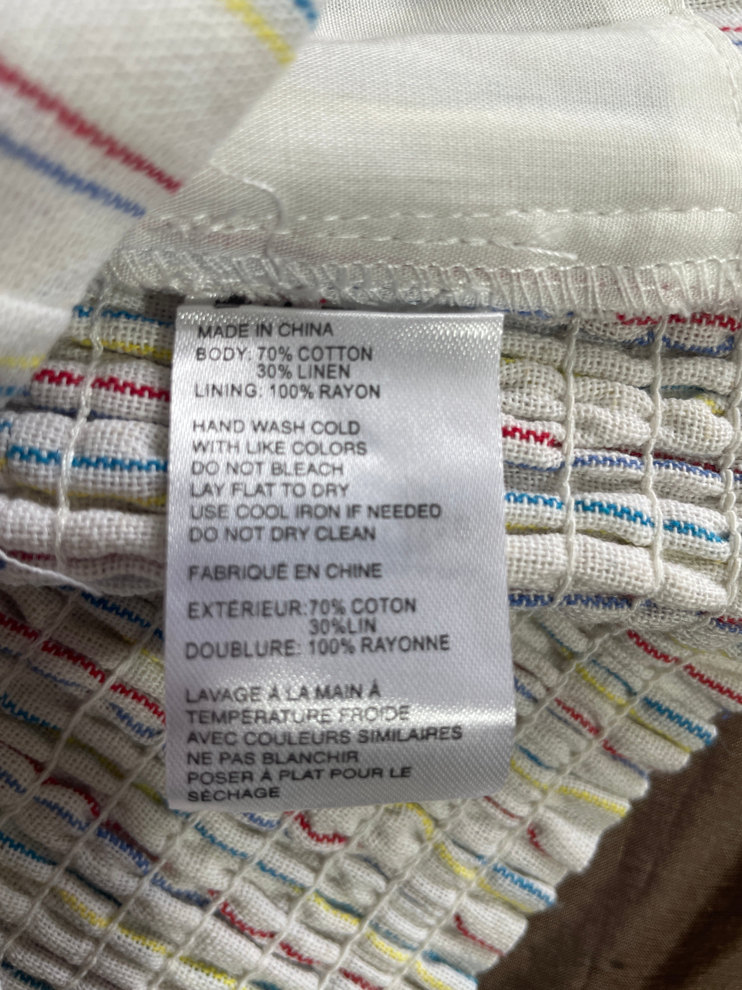 Close-up of a sewn-on fabric care label on a striped textile, showing text including 'MADE IN CHINE' and material details in English and French.