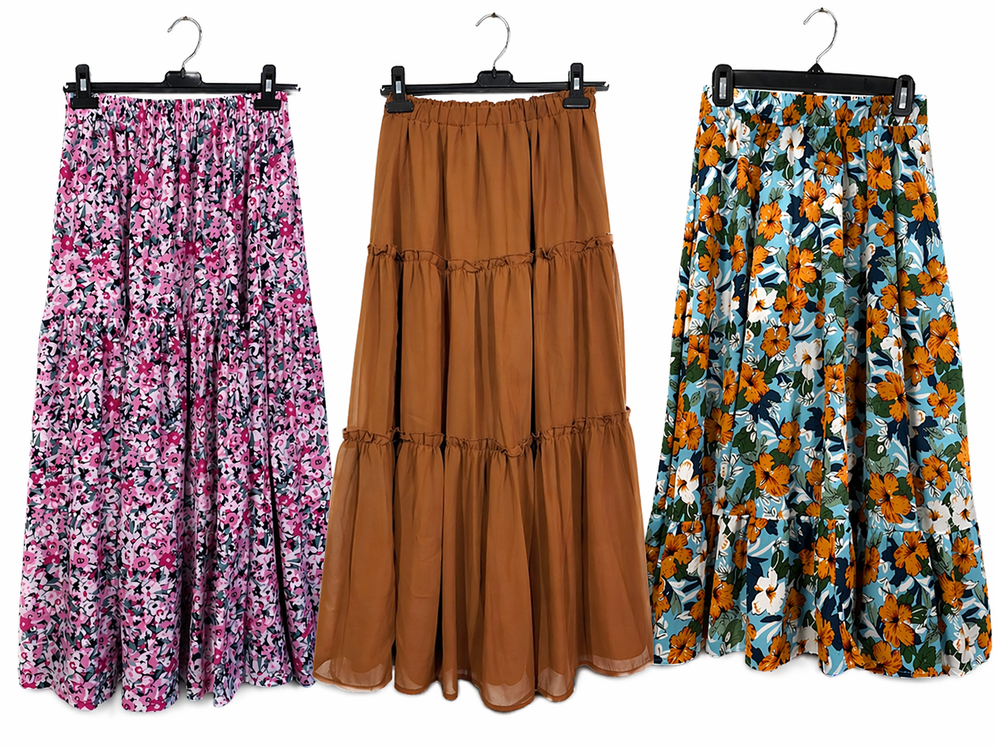 Three floral and tiered skirts on hangers against a white background