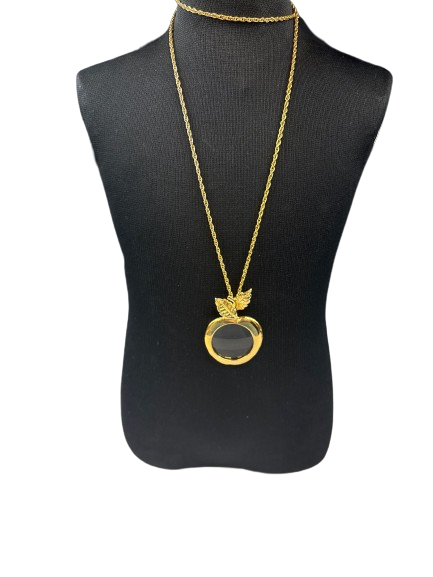 Vintage gold tone apple magnifying glass necklace on display stand