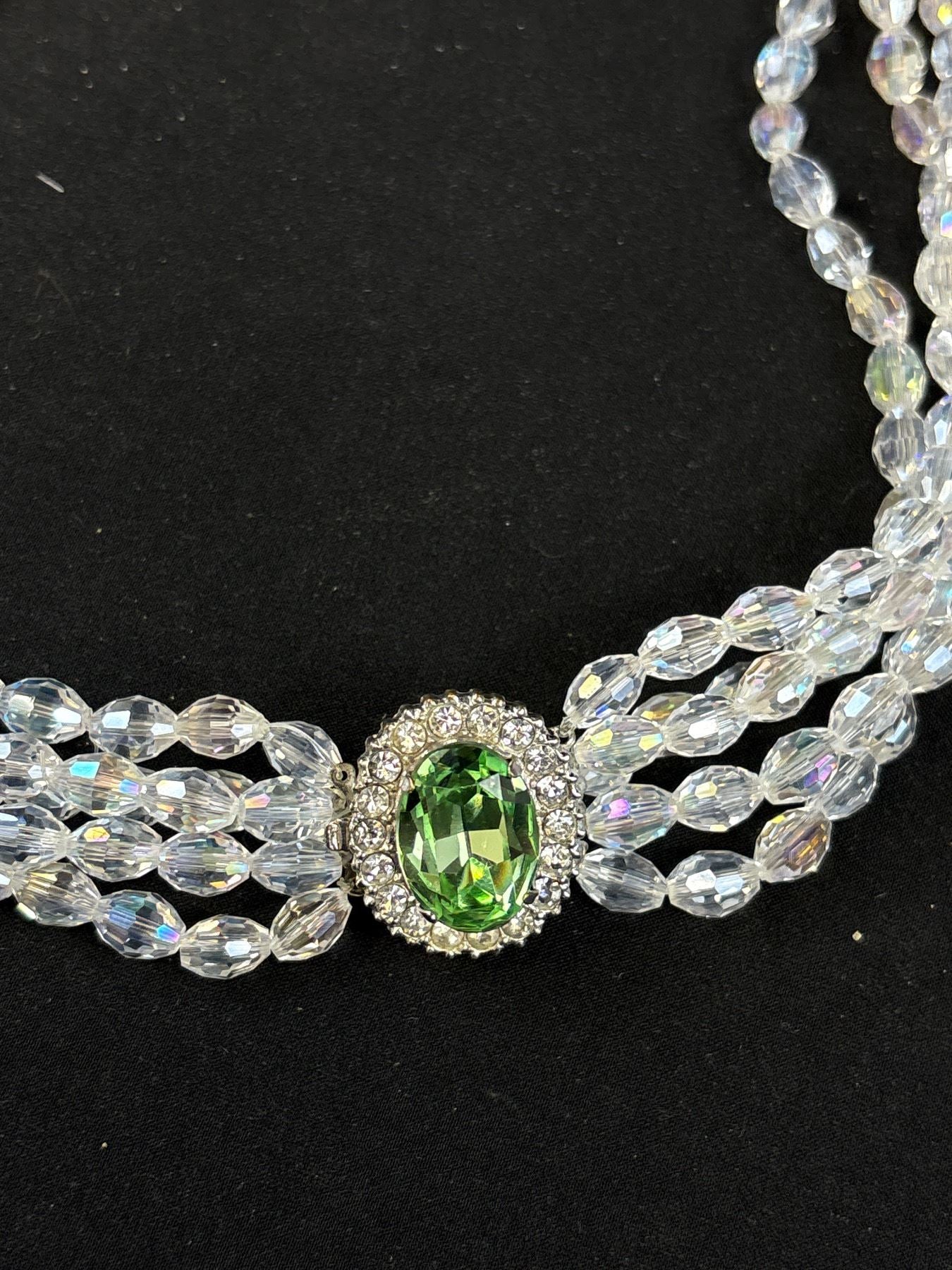 Necklace with a green gemstone and clear beads on a black background