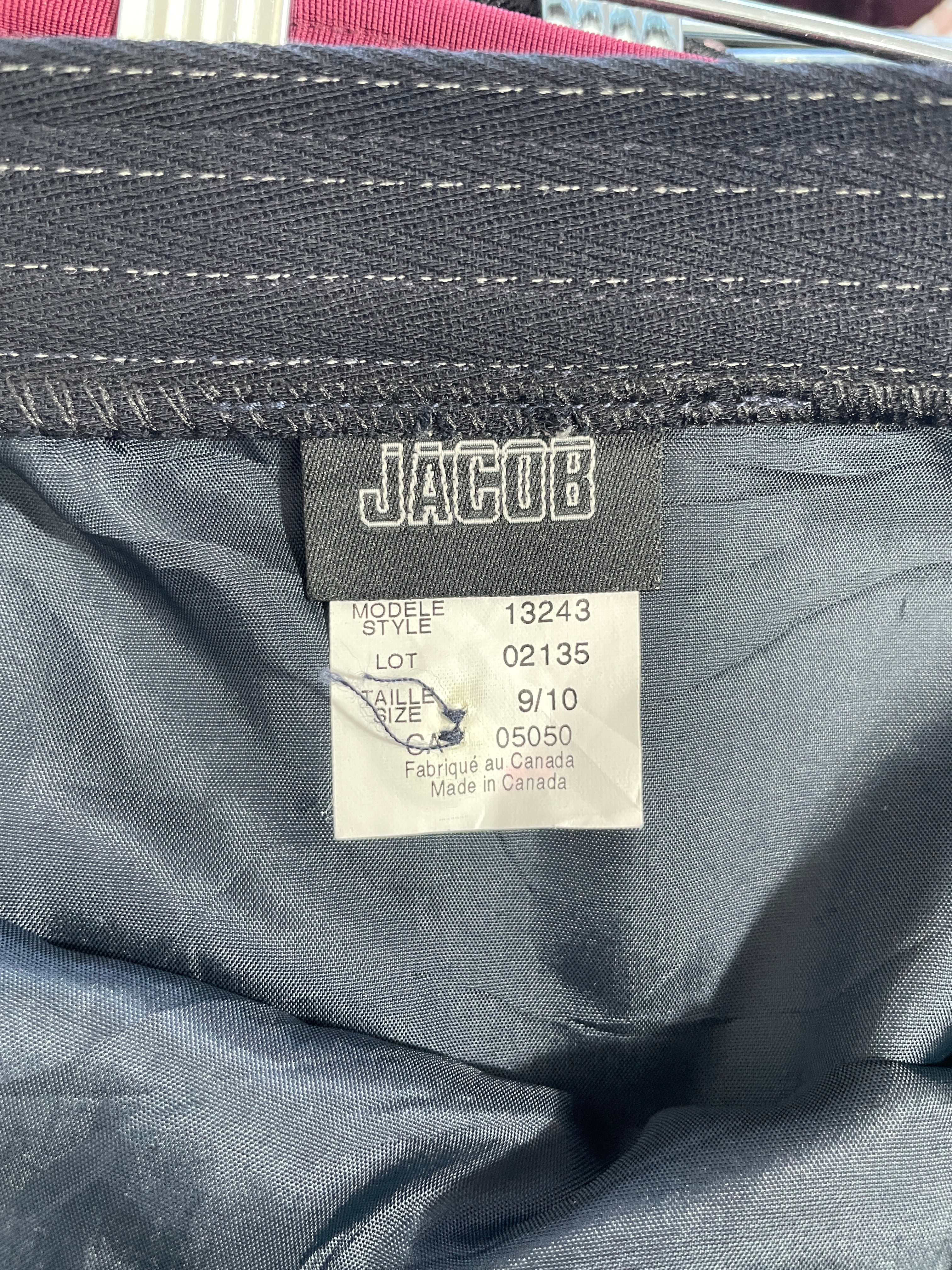 Close-up of the inside waistband of dark gray or black denim jeans, showing a Jacquob brand label and a white size tag.