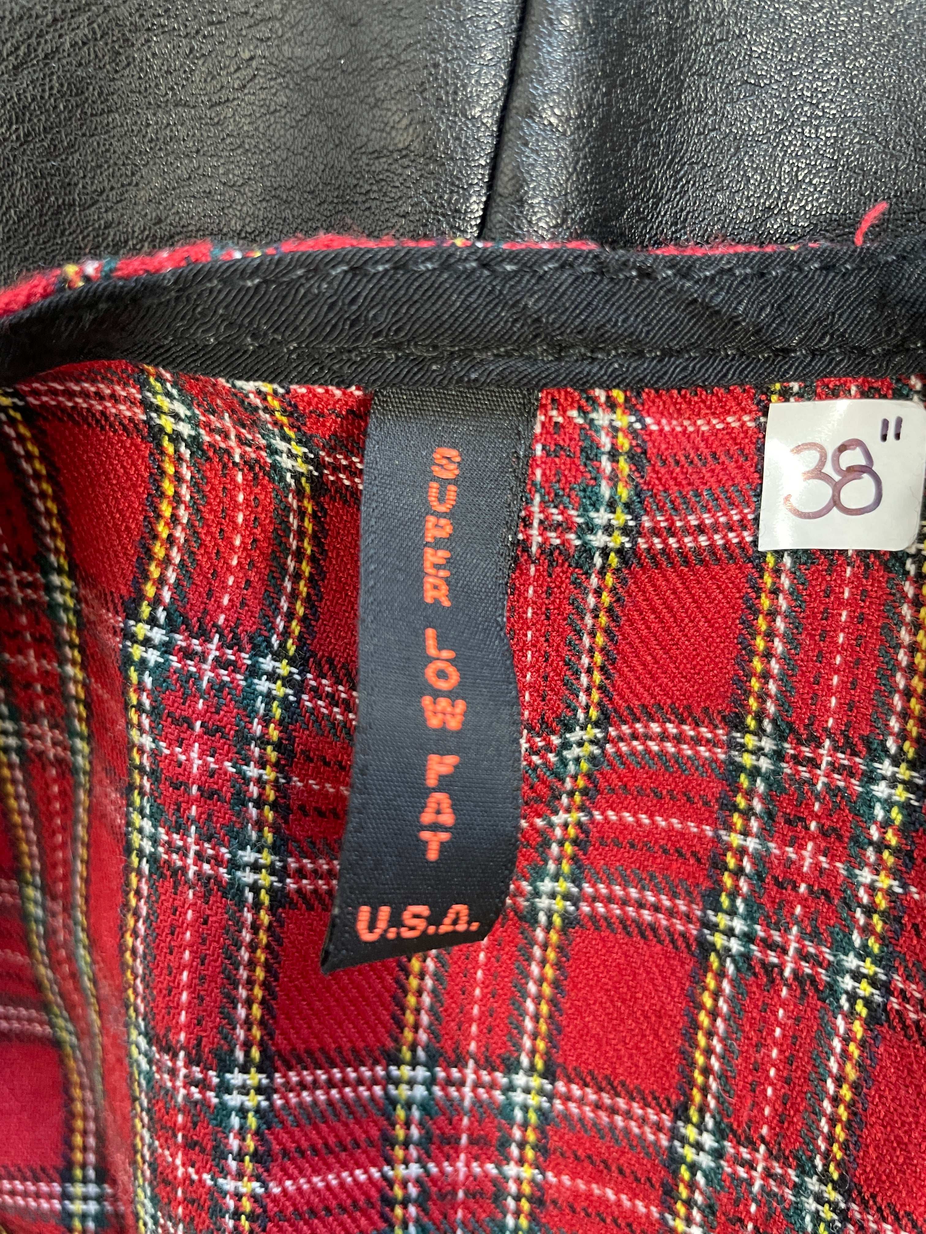 Close-up of a red tartan plaid garment interior with a black size tag reading 38 and a black brand tag reading Super Low Fat U.S.