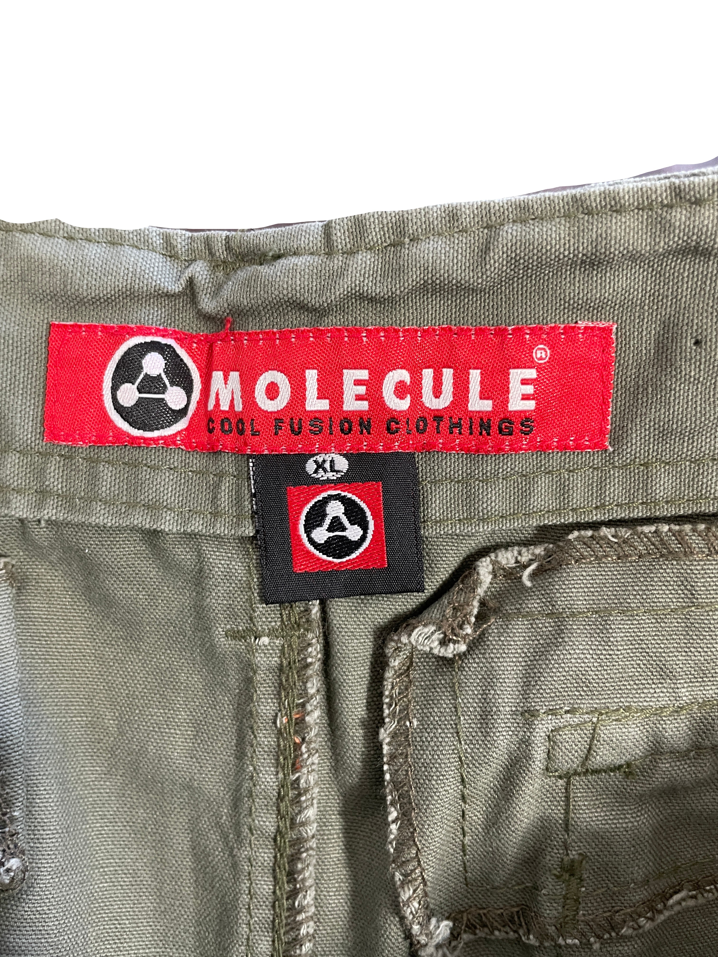 Close-up of the waistband of olive green pants showing a red and black 'MOLECULE COOL FUSION CLOTHING' brand label and a black size tag marked 'XL'.