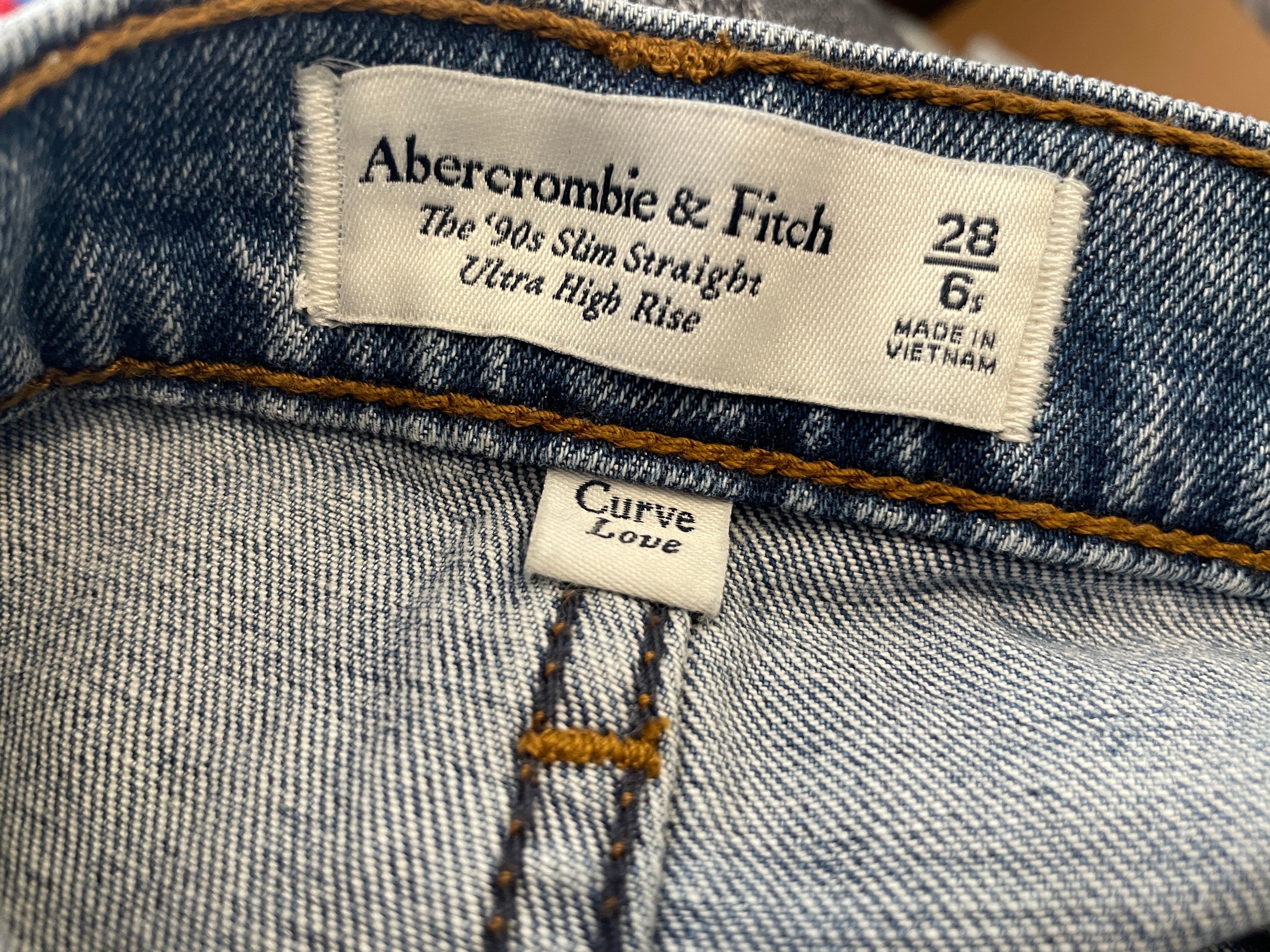 Close-up of the inner waistband of a blue denim jeans showing the Abercrombie & Fitch brand label and the Curve Love fit label.