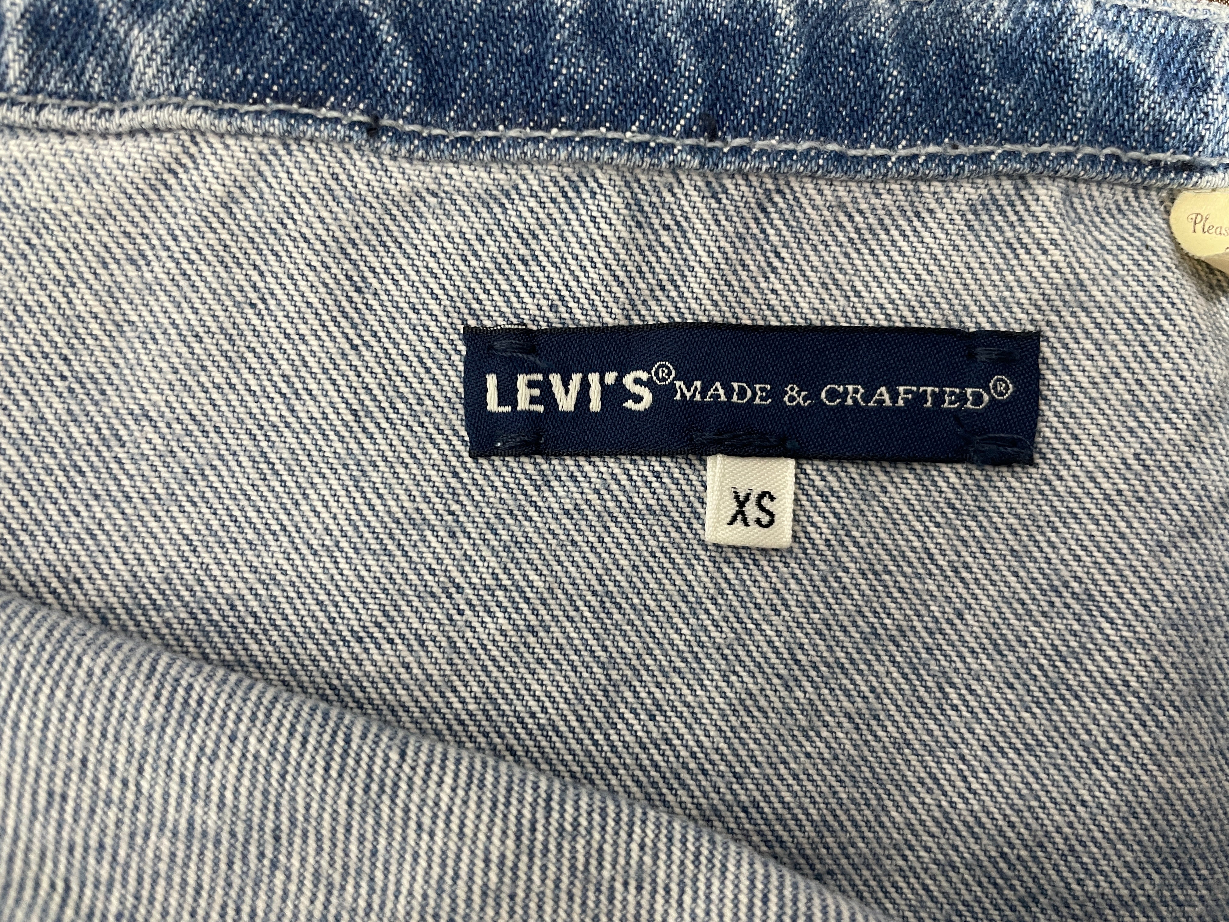 Close-up of a denim garment showing the interior waistband and a Levi's Made & Crafted label with an XS size tag.