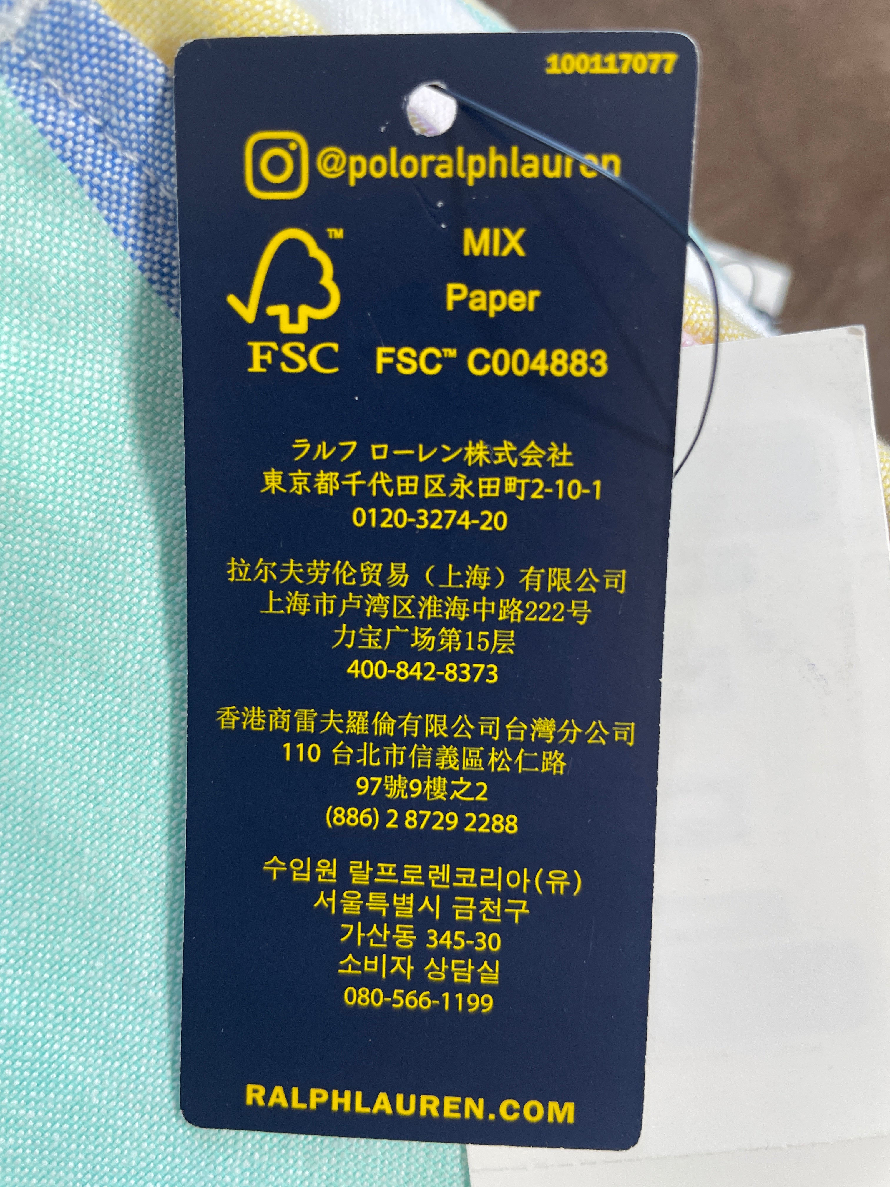 A close-up of a dark blue Ralph Lauren garment care tag with yellow text and logos, including '@poloralphaurcn', 'MIX Paper', 'FSC', and 'RALPHLAUREN.COM'.
