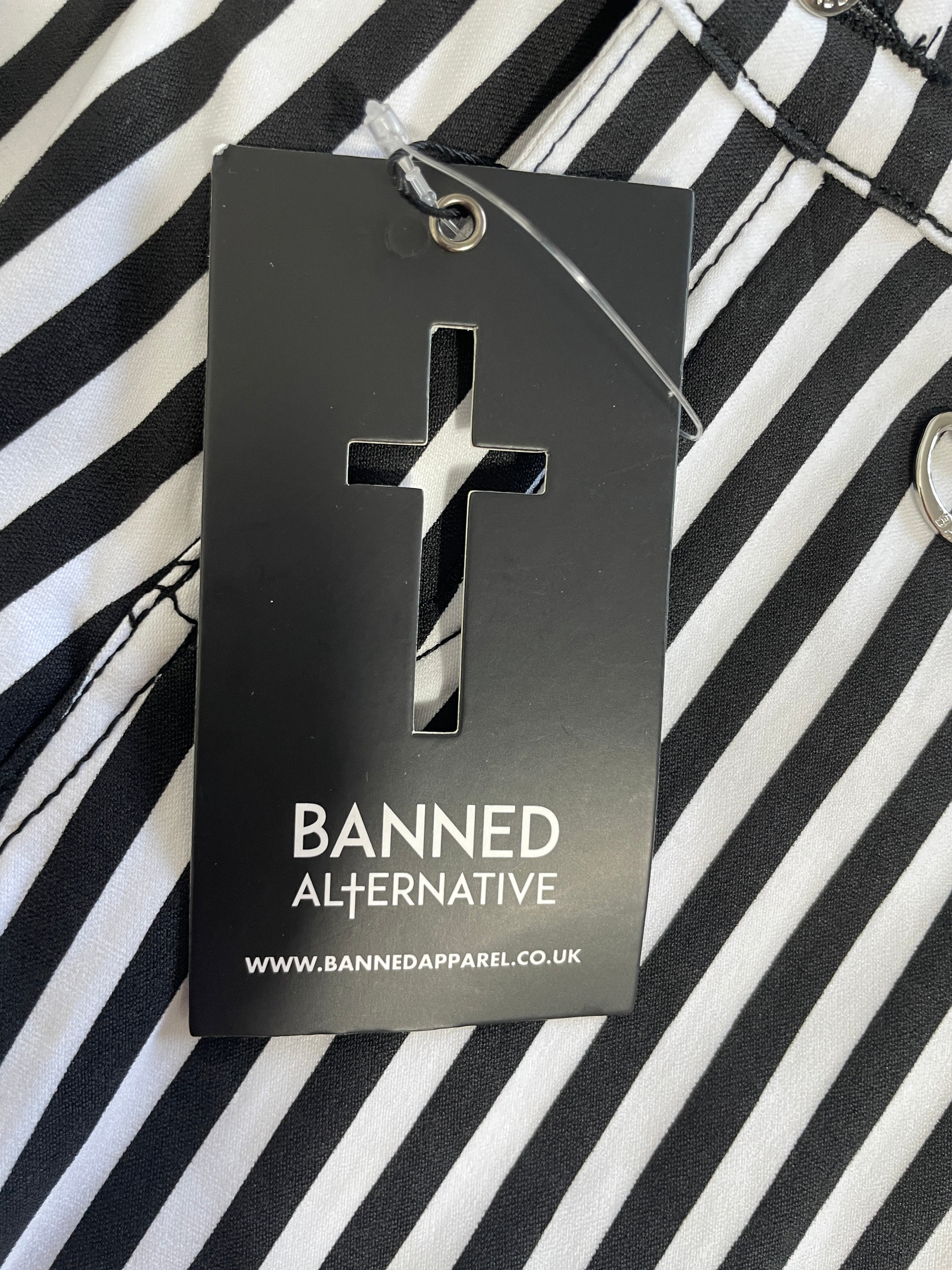 A black hangtag with a cross-shaped cutout and white text reading 'BANNED ALTERNATIVE' and 'WWW.BANNEDAPPAREL.