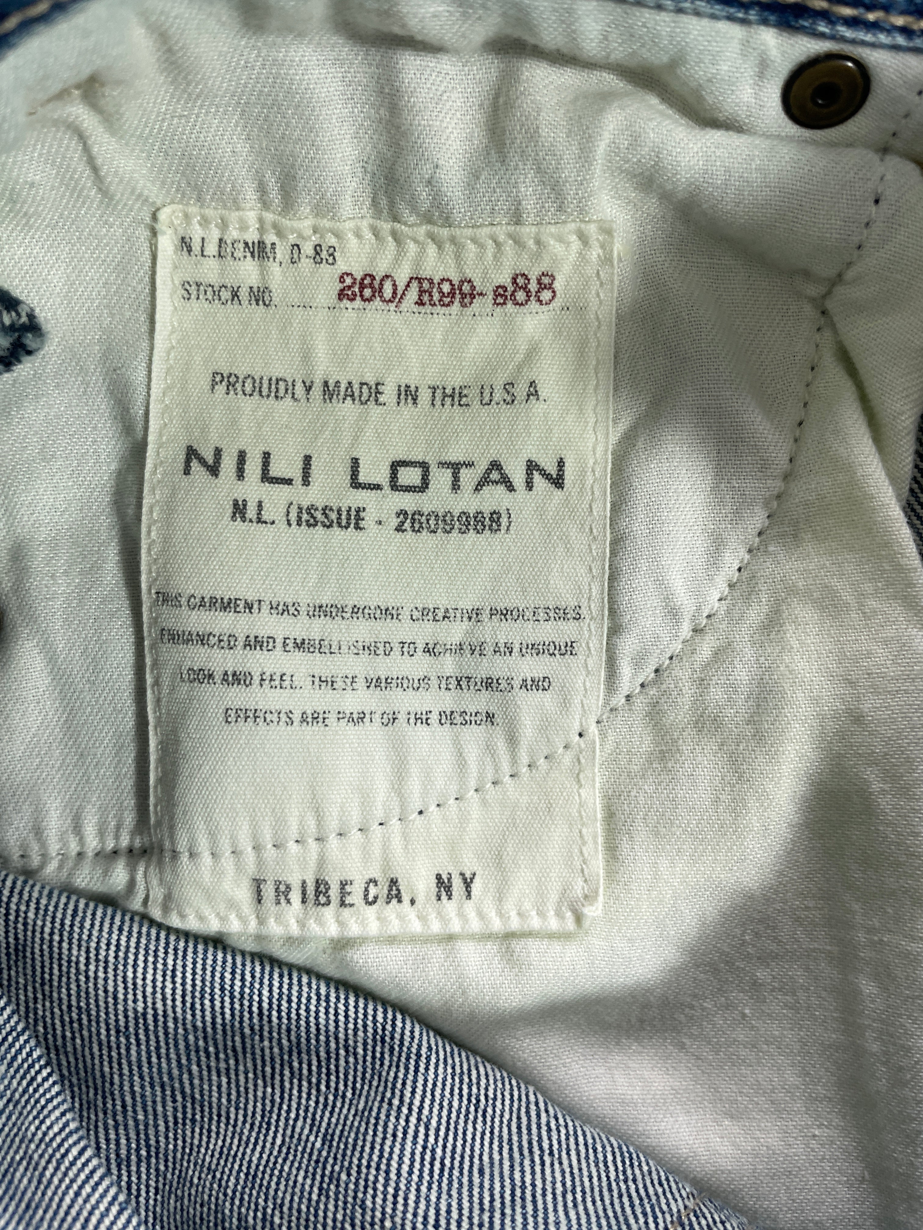 Close-up of the inner neck label of a denim garment, showing the brand 'Nili Lotan' and 'Tribeca, NY' printed on a cream-colored tag, with light blue denim fabric visible around it.