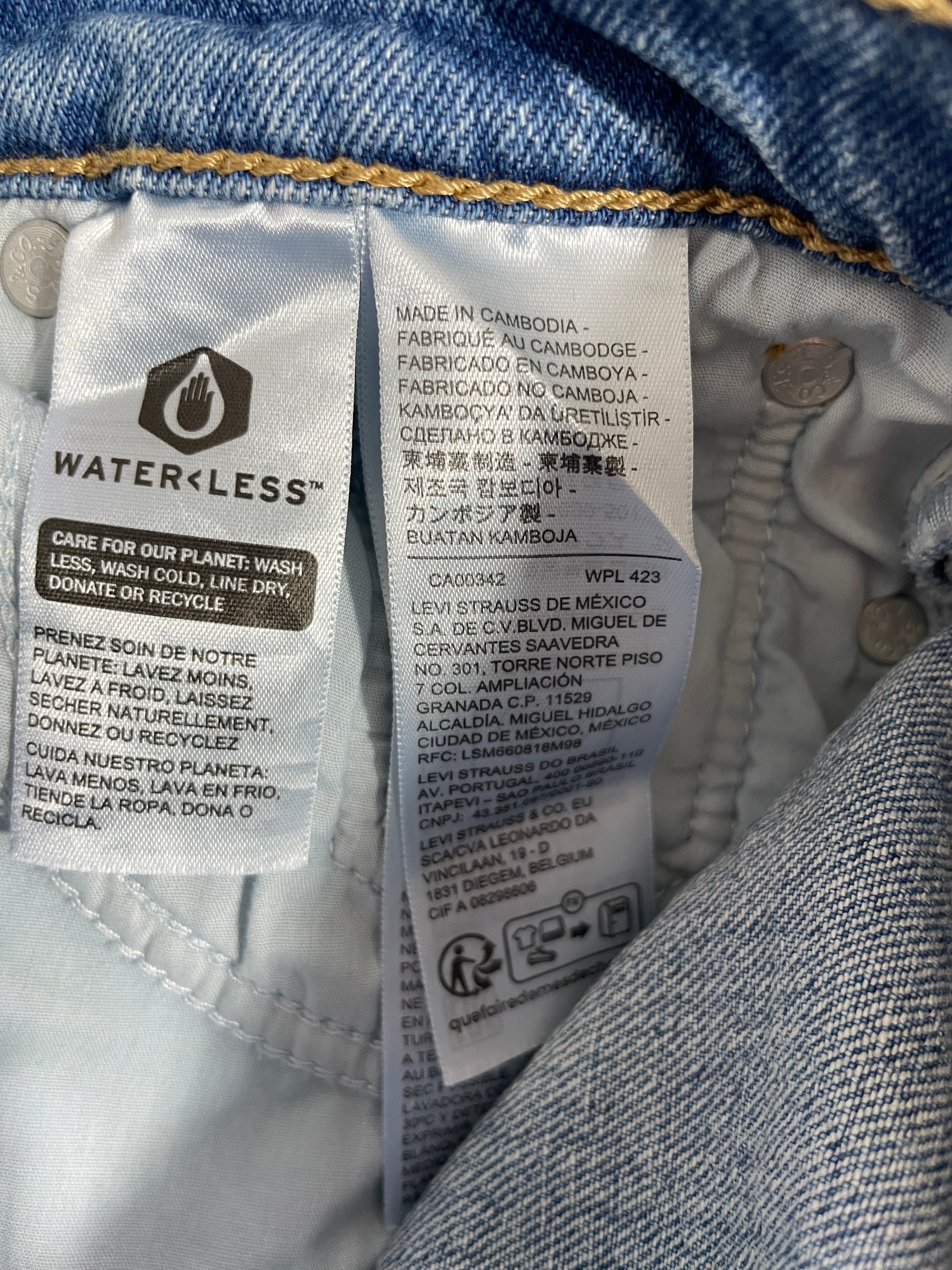 Close-up of the inside neck label of a Levi's Waterless denim garment, showing care instructions, material info, and branding on a blue denim fabric background.