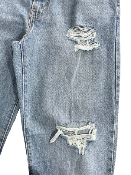 Close-up of light-wash blue denim jeans with distressed rips and frayed detailing on the leg, shown against a plain white background.