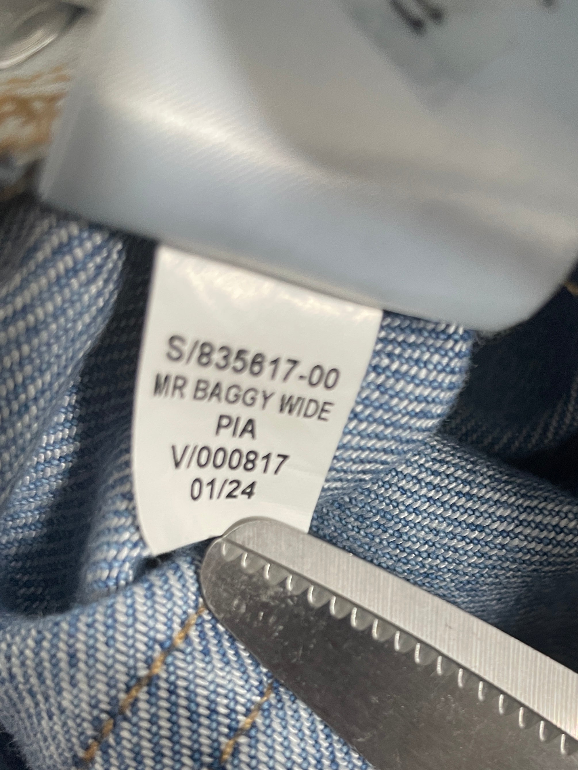 Close-up of a denim garment interior showing a white size tag 