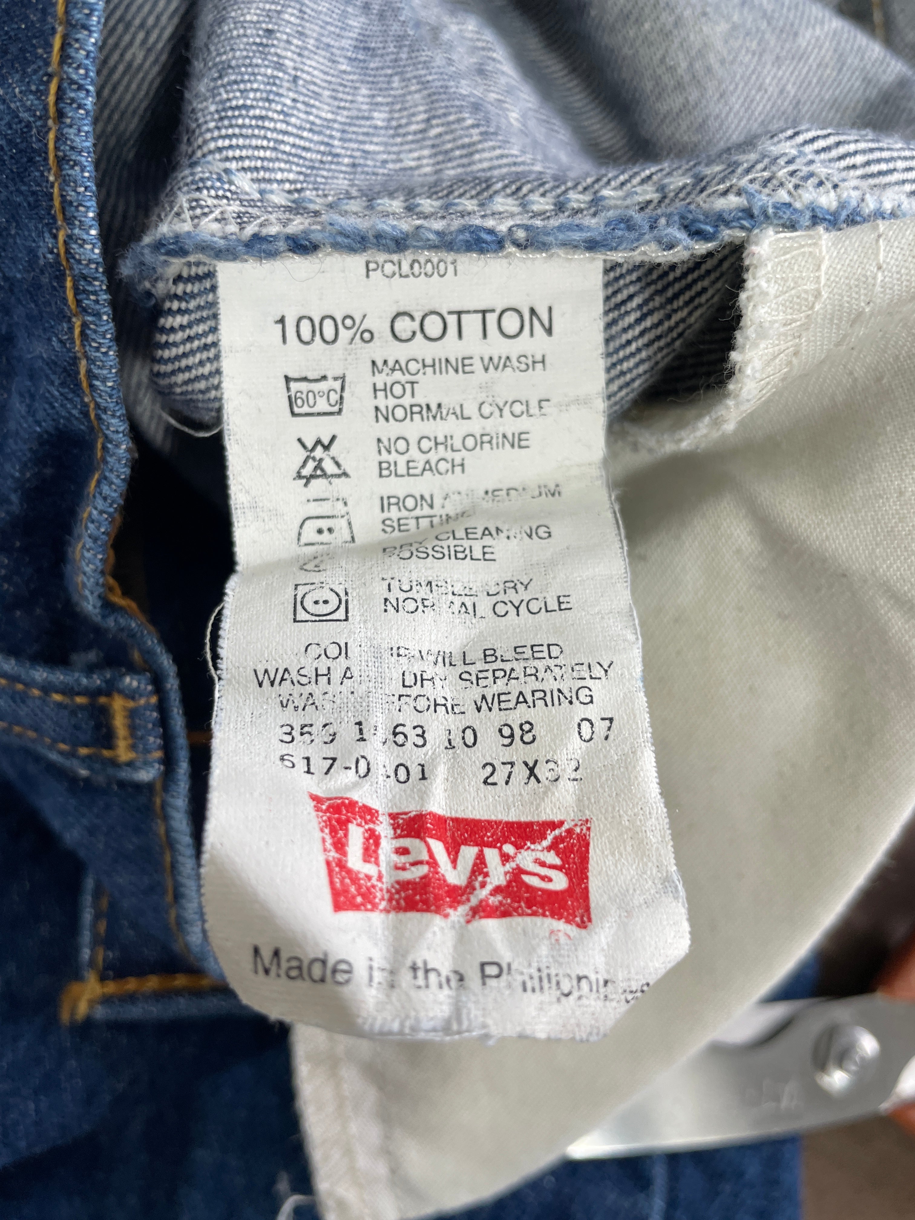 Close-up of a Levi's cotton garment label sewn inside blue denim jeans, showing the red Levi's logo and care instructions.