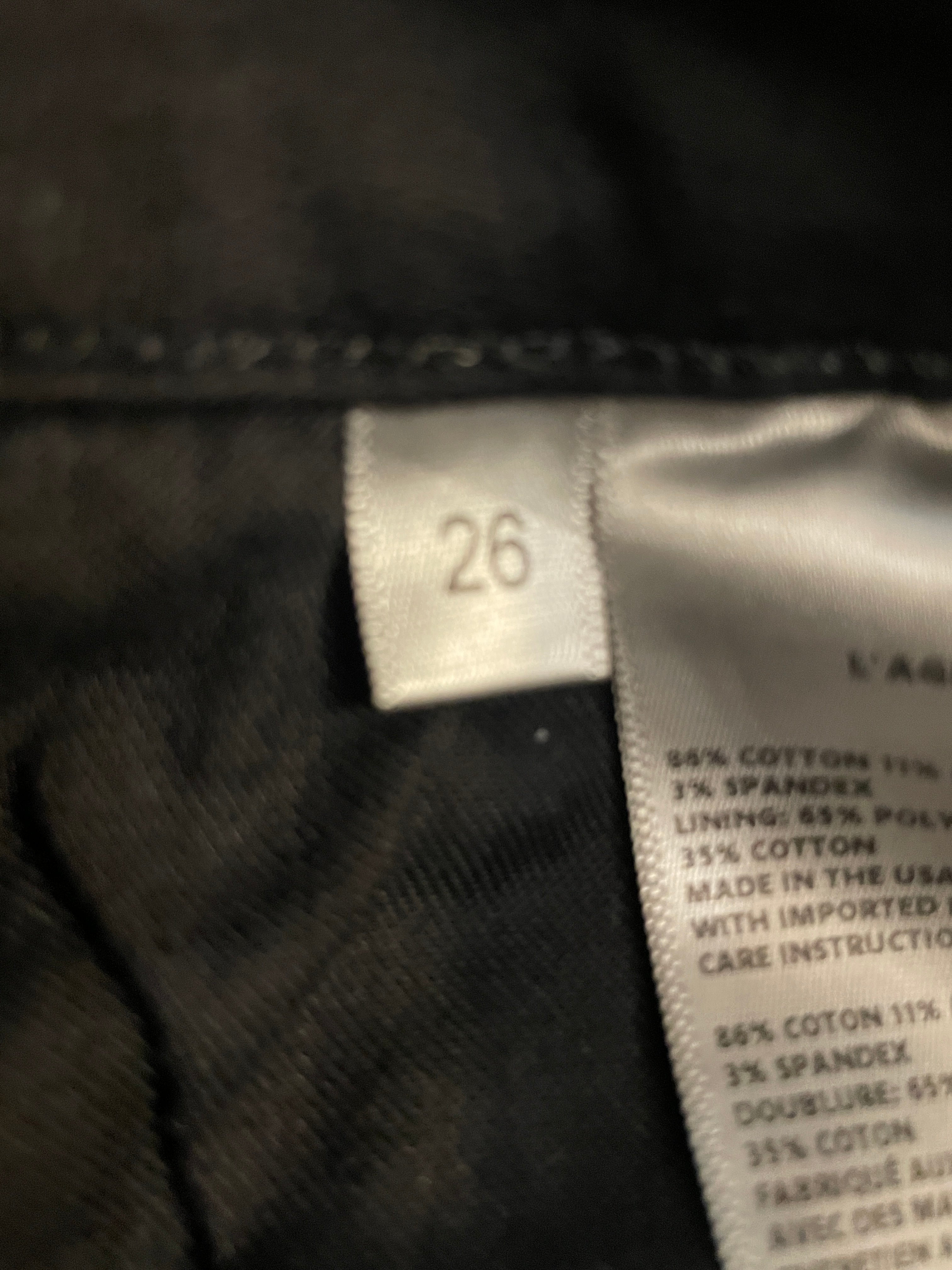 Close-up of a garment label showing size 26 and fabric composition details on a dark garment.