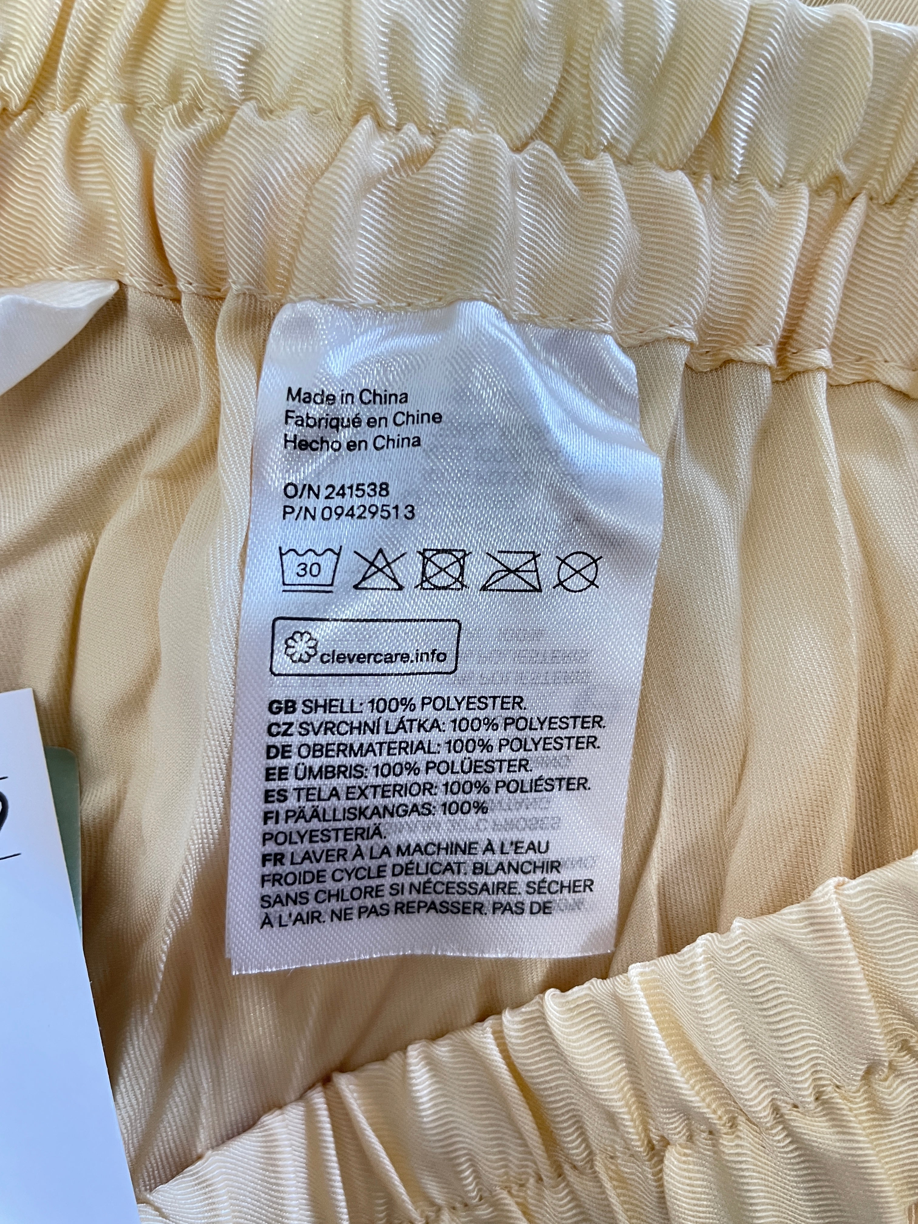 H&M 100 percent polyester fabric composition and care label on cream skirt