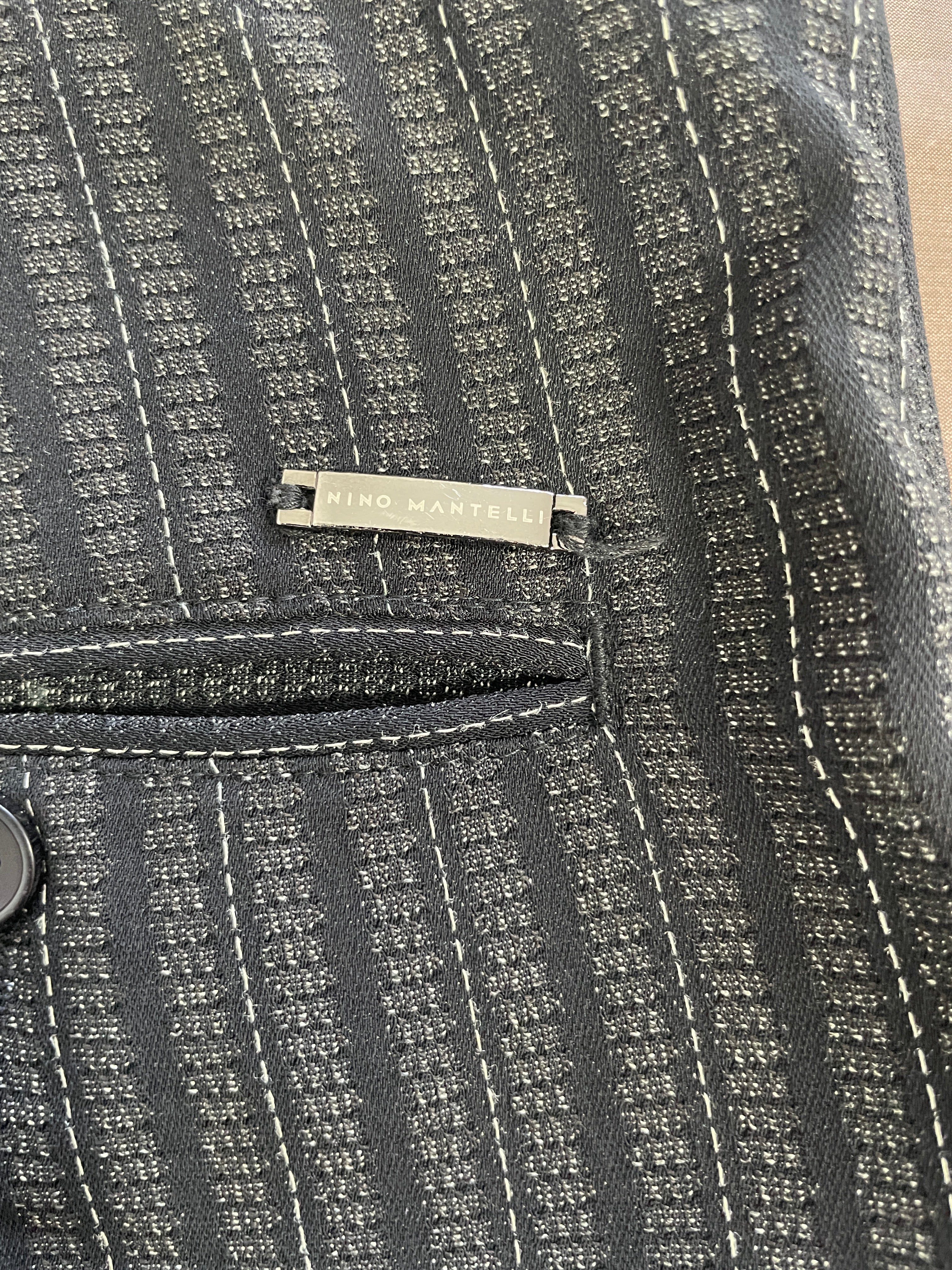 Close-up of Nino Mantelli Designs metal brand label and textured striped fabric