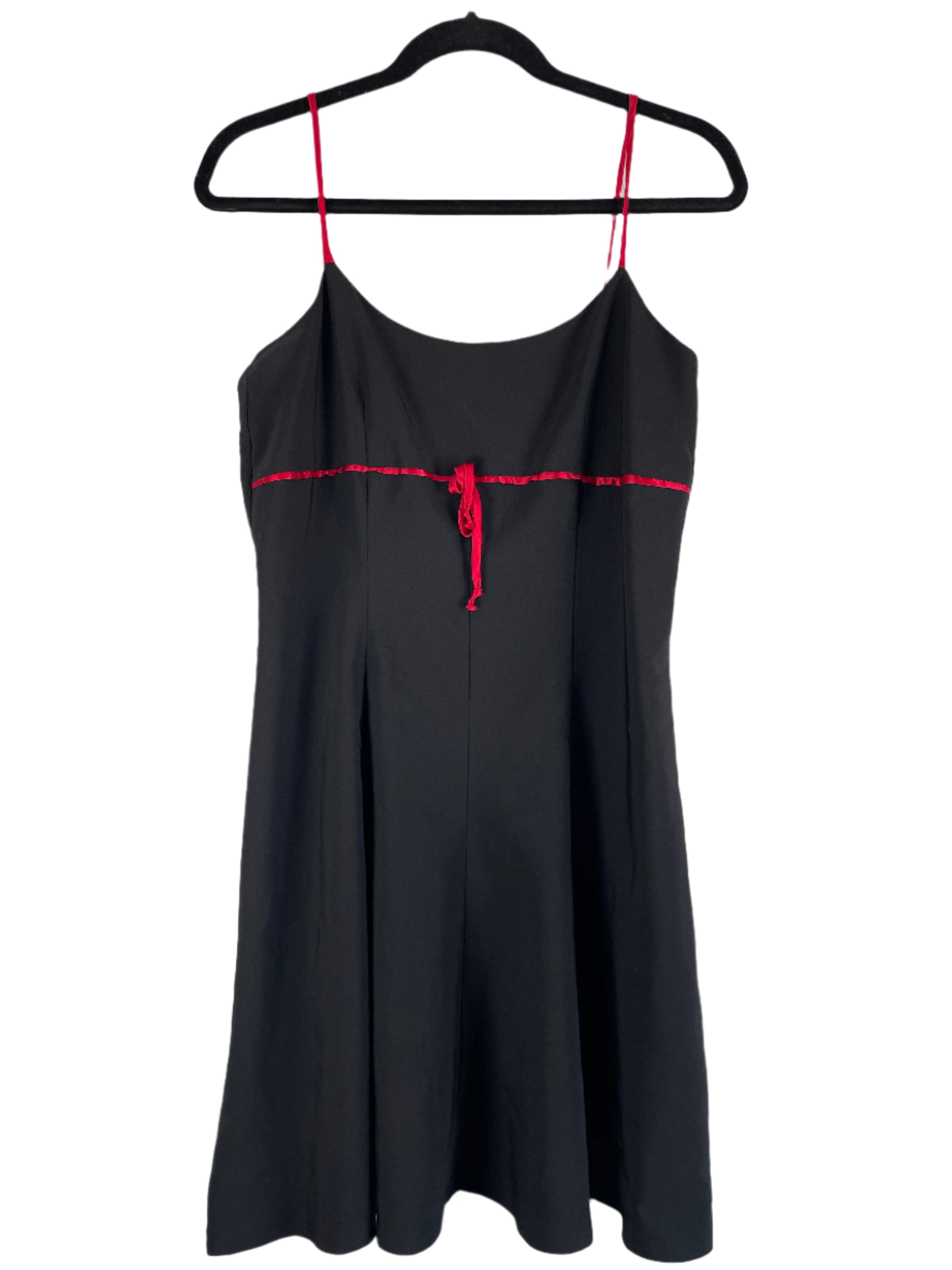 Black dress with red stitching on a hanger against a white background
